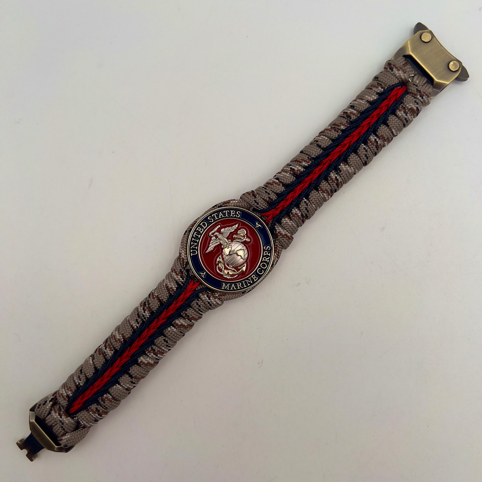 Thick and comfortable braided United States Marine Corps bracelet featuring a 24K gold and silver plated USMC officer Eagle Globe and Anchor medallion, a Cobra style tactical buckle and woven with Desert Camo 550 paracord and Imperial red and black micro cord.