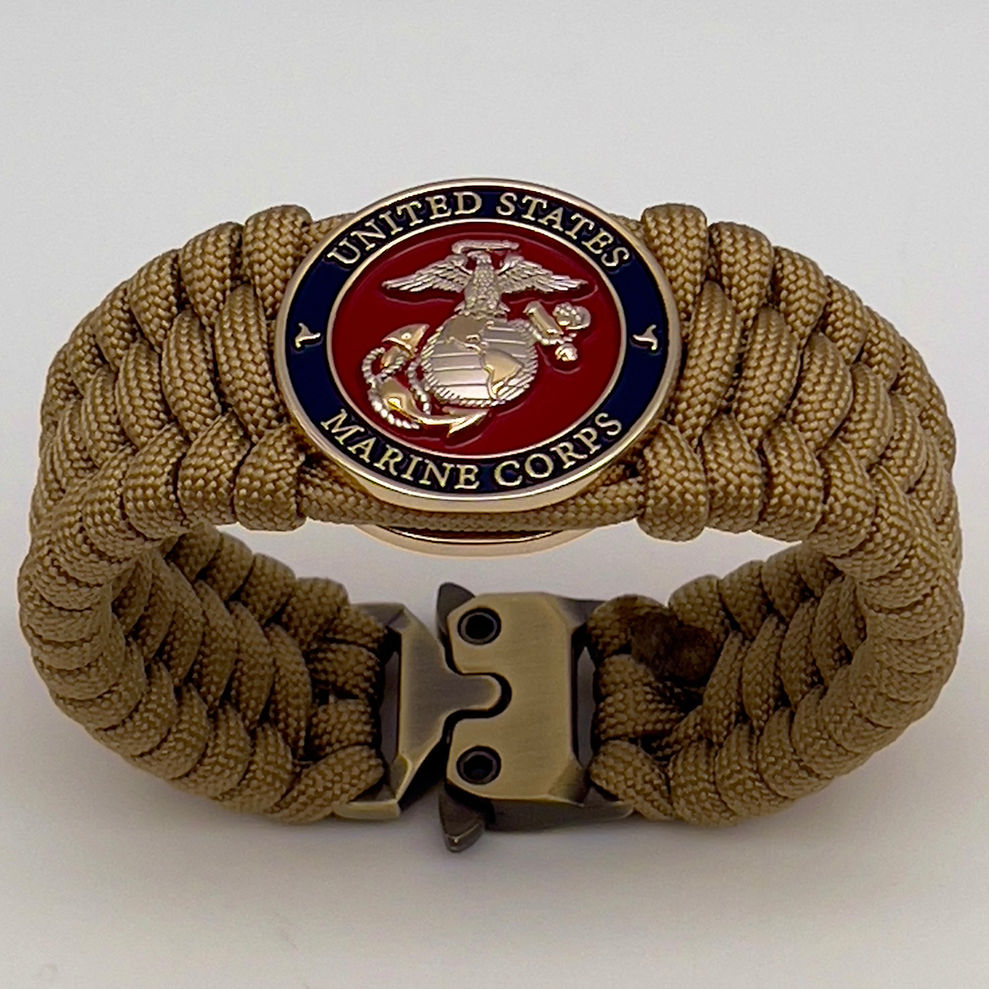 Thick and comfortable braided United States Marine Corps bracelet featuring a 24K gold and silver plated USMC officer Eagle Globe and Anchor medallion, a Cobra style tactical buckle and woven with gold 550 paracord.
