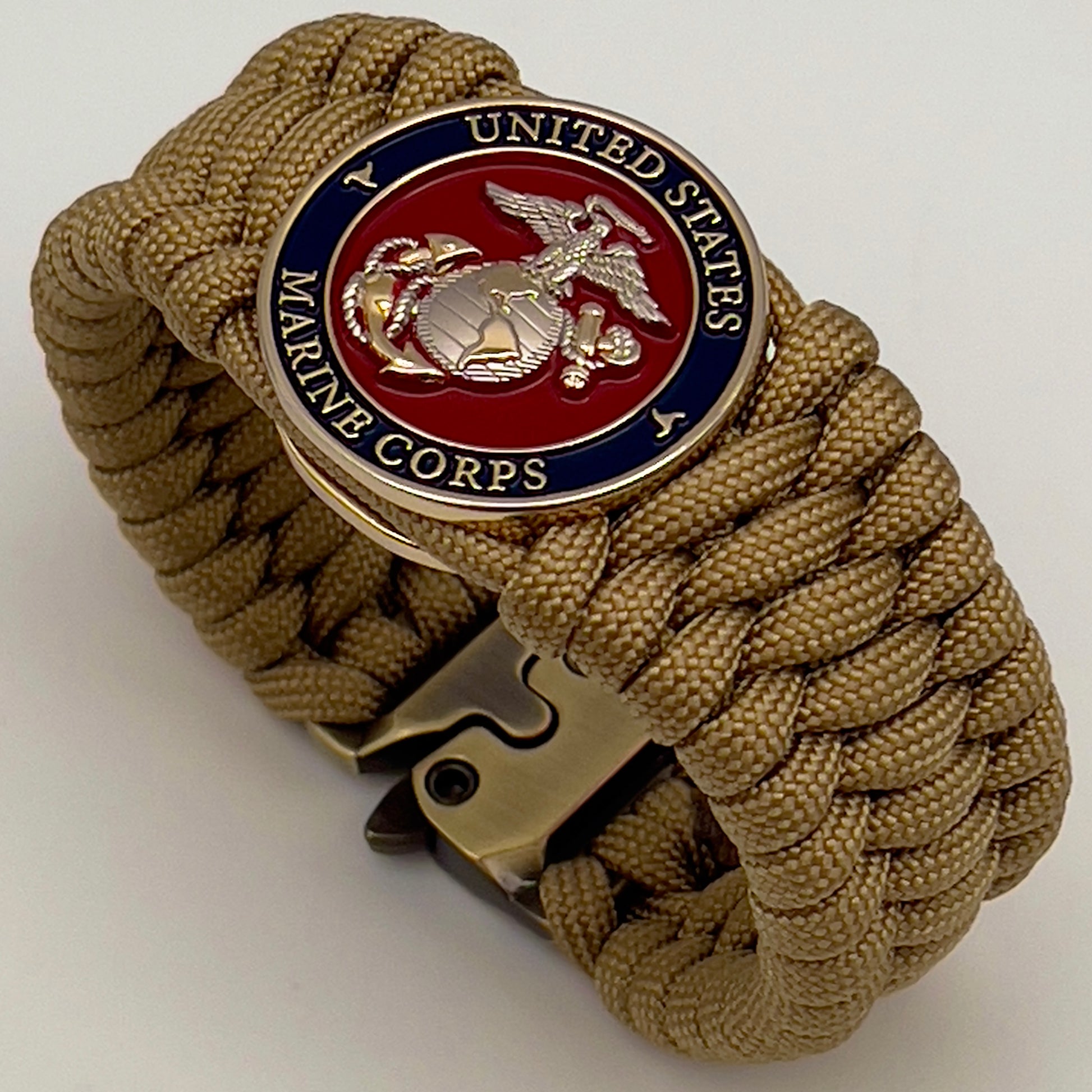 Thick and comfortable braided United States Marine Corps bracelet featuring a 24K gold and silver plated USMC officer Eagle Globe and Anchor medallion, a Cobra style tactical buckle and woven with gold 550 paracord.