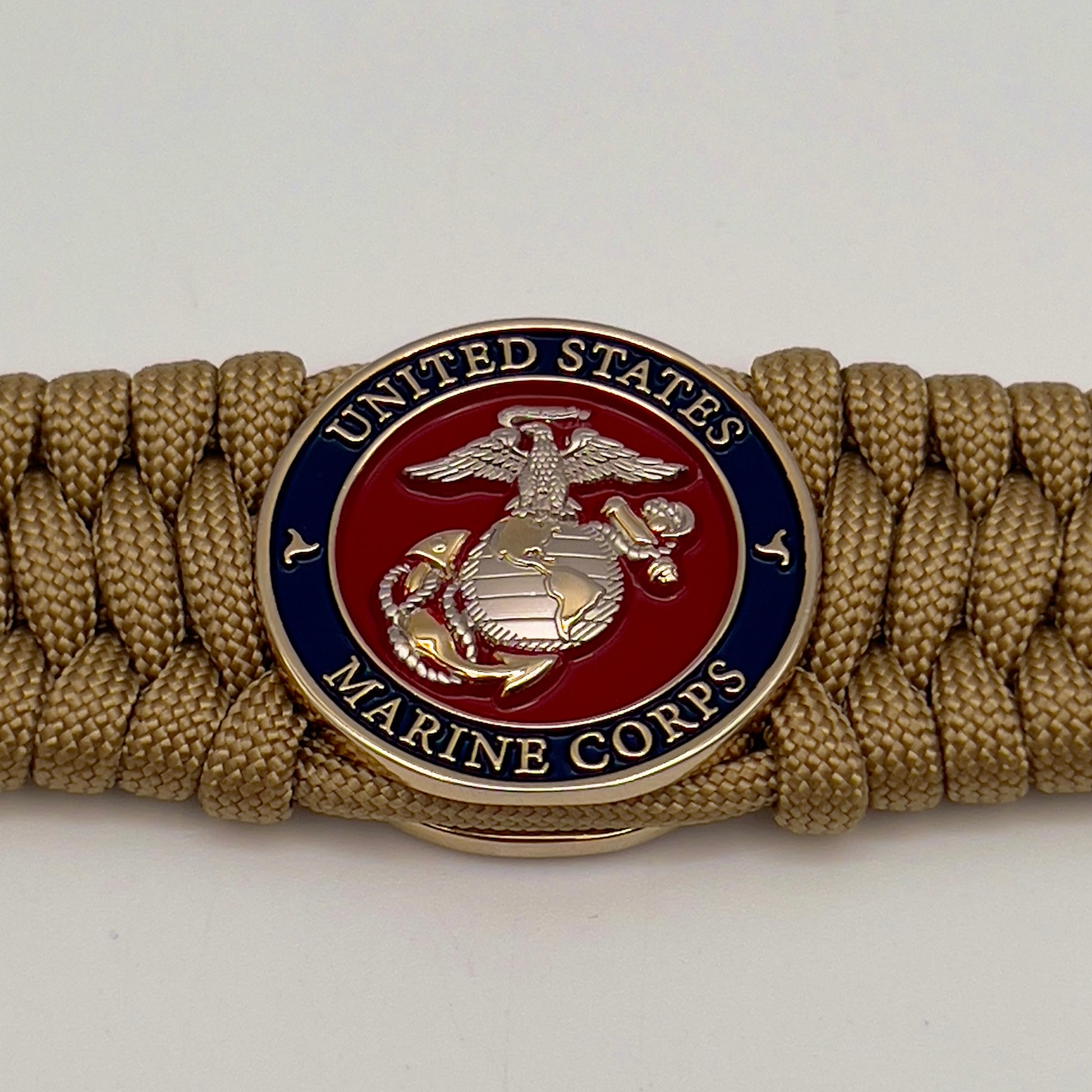 Thick and comfortable braided United States Marine Corps bracelet featuring a 24K gold and silver plated USMC officer Eagle Globe and Anchor medallion, a Cobra style tactical buckle and woven with gold 550 paracord.