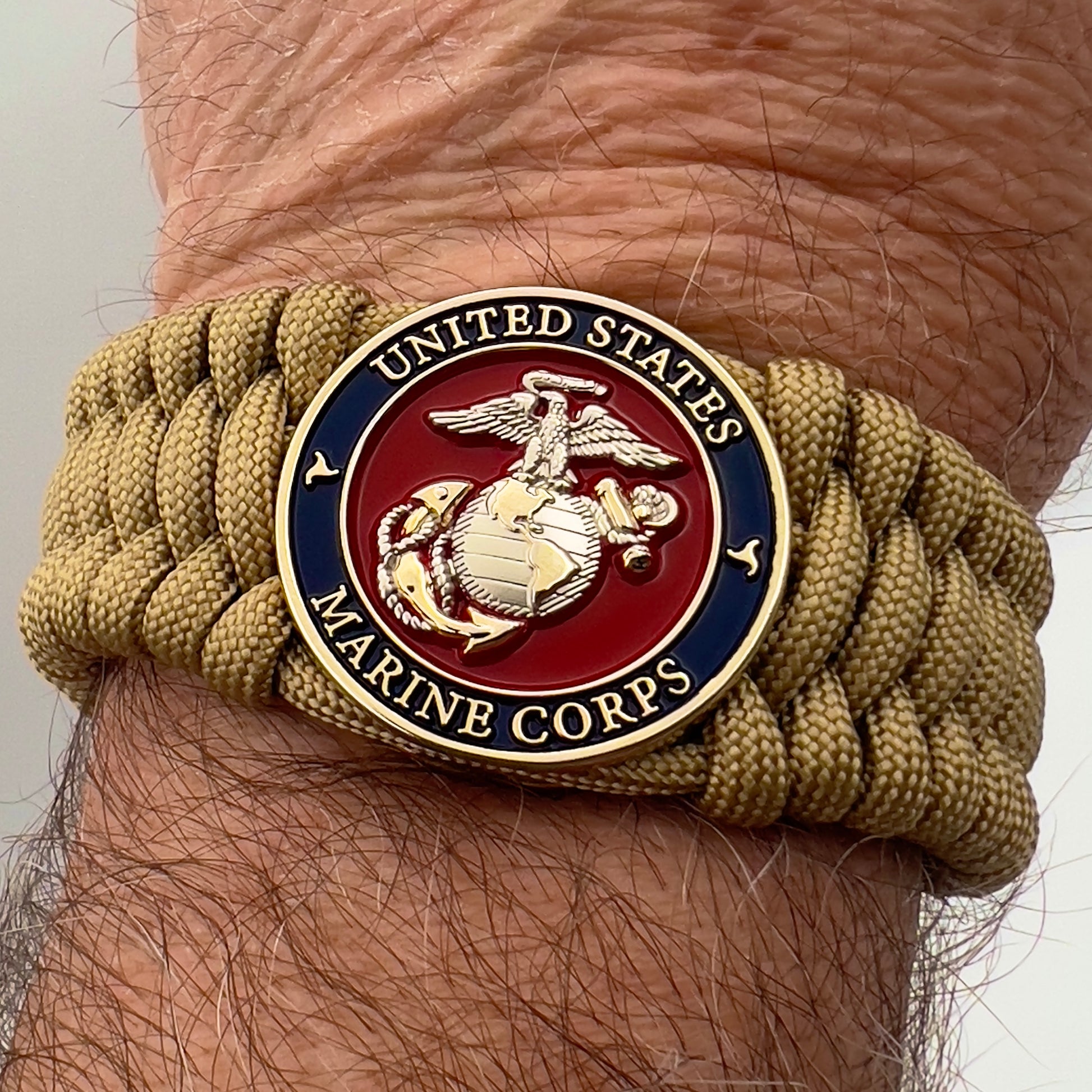 Thick and comfortable braided United States Marine Corps bracelet featuring a 24K gold and silver plated USMC officer Eagle Globe and Anchor medallion, a Cobra style tactical buckle and woven with gold 550 paracord.