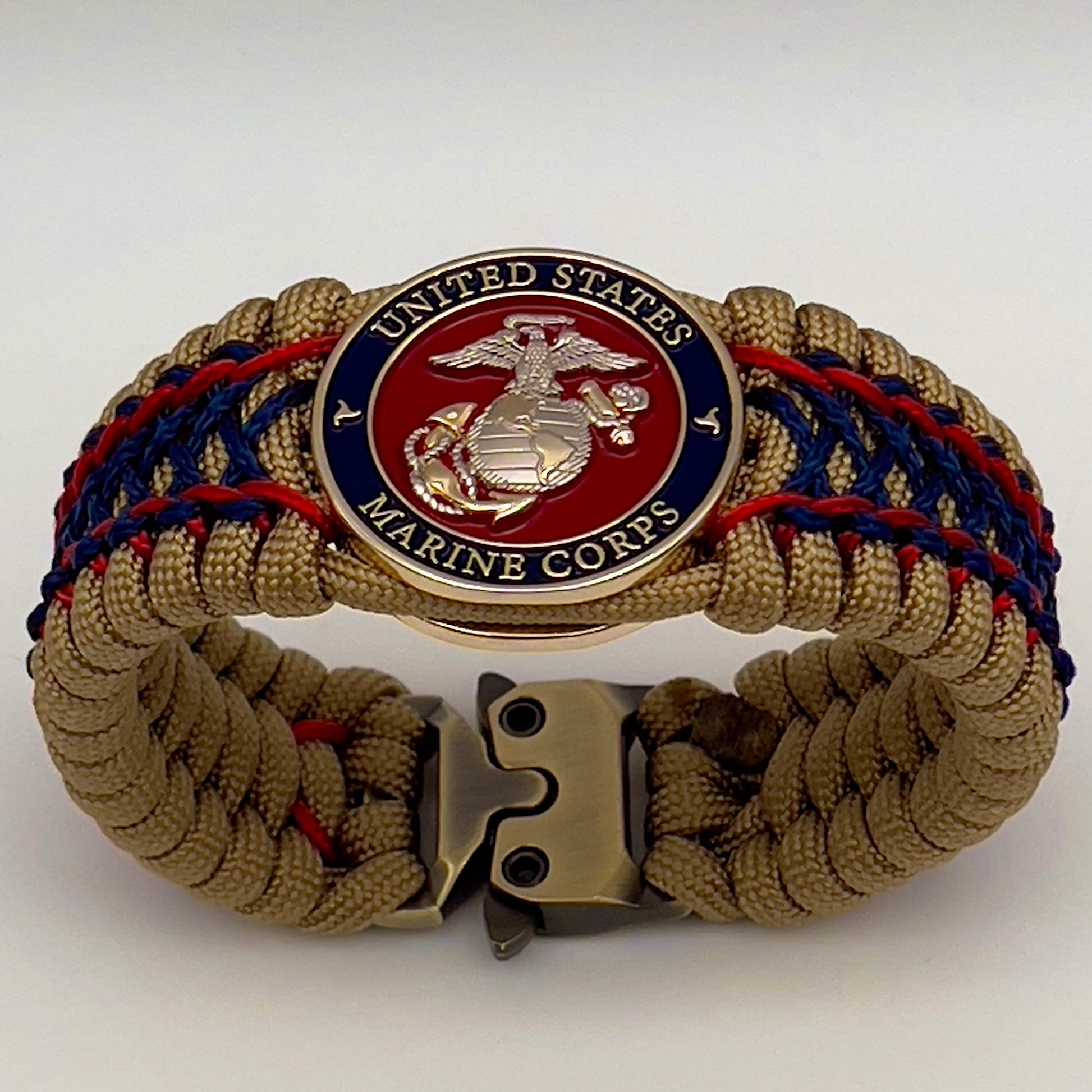 Thick and comfortable braided United States Marine Corps bracelet featuring a 24K gold and silver plated USMC officer Eagle Globe and Anchor medallion, a gold Cobra style tactical buckle and woven with gold 550 paracord and Imperial Red and Navy Blue micro cord.