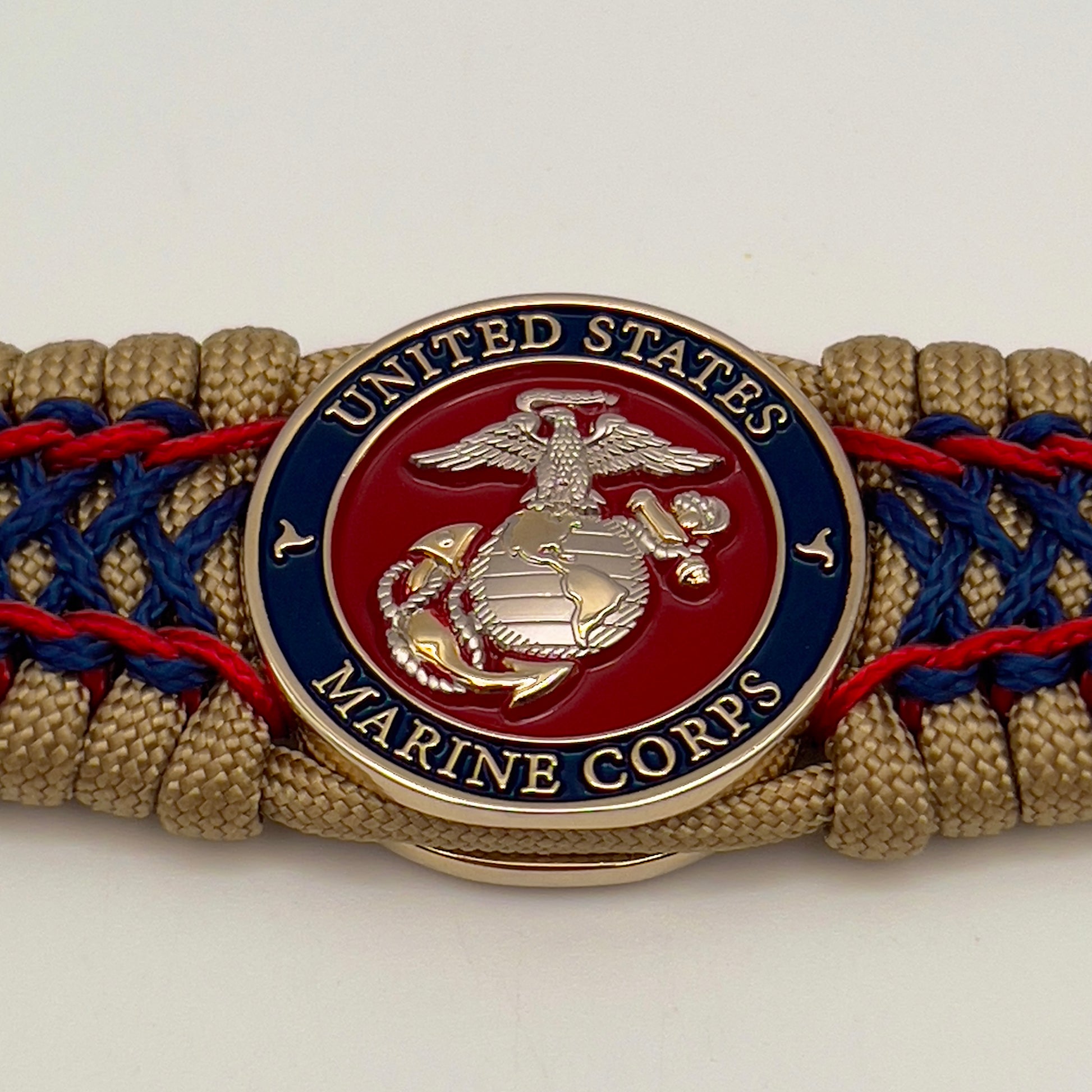Thick and comfortable braided United States Marine Corps bracelet featuring a 24K gold and silver plated USMC officer Eagle Globe and Anchor medallion, a gold Cobra style tactical buckle and woven with gold 550 paracord and Imperial Red and Navy Blue micro cord.