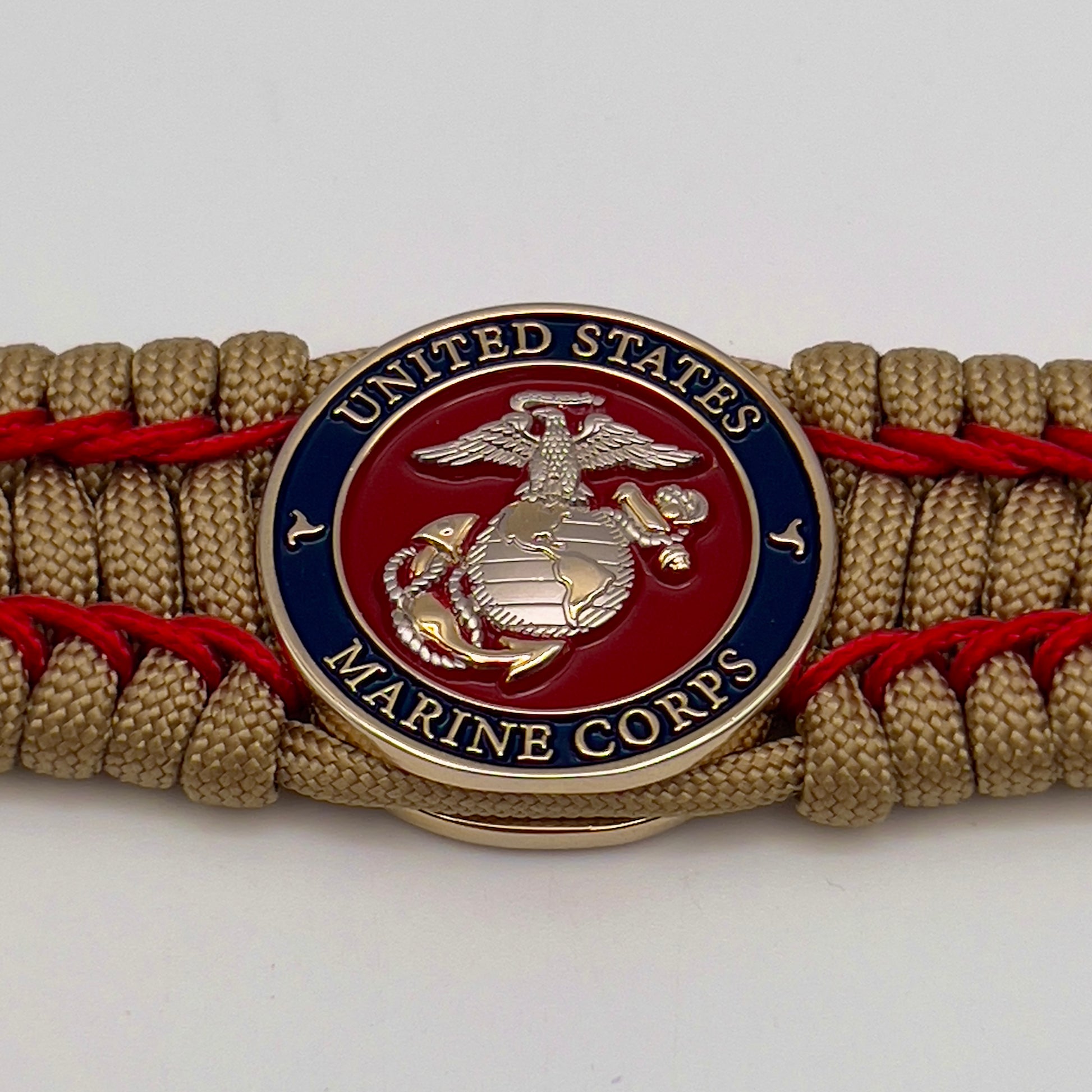 Thick and comfortable braided United States Marine Corps bracelet featuring a 24K gold and silver plated USMC officer Eagle Globe and Anchor medallion, a gold Cobra style tactical buckle and woven with gold 550 paracord and Imperial Red micro cord.