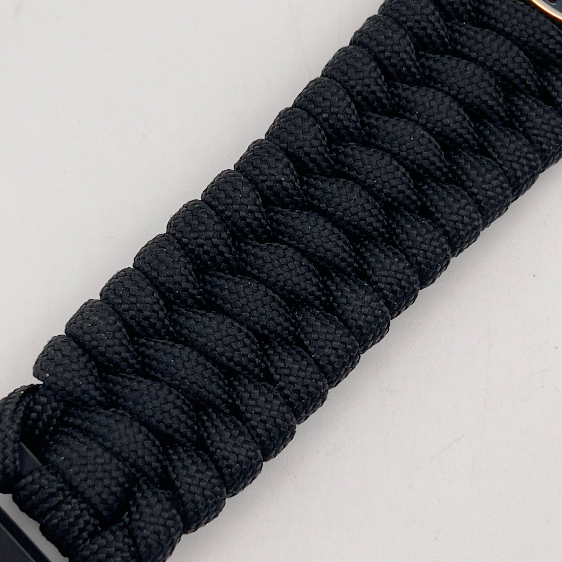 Thick and comfortable braided United States Marine Corps bracelet featuring a 24K gold and silver plated USMC officer Eagle Globe and Anchor medallion, a black Cobra style tactical buckle and woven with black 550 paracord.