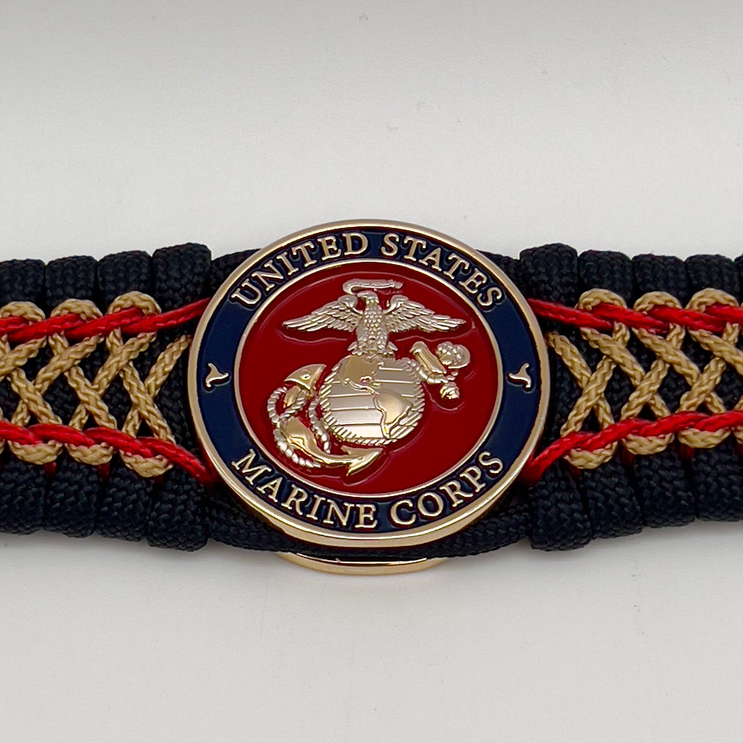 Thick and comfortable braided United States Marine Corps bracelet featuring a 24K gold and silver plated USMC officer Eagle Globe and Anchor medallion, a black Cobra style tactical buckle and woven with black 550 paracord and Imperial Red and gold micro cord.
