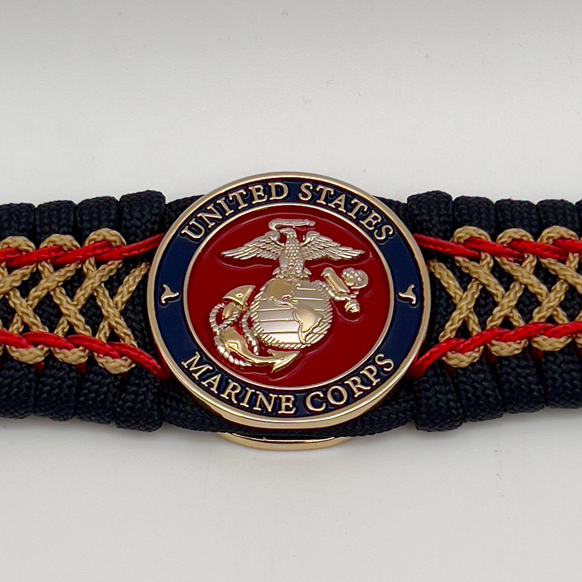 Thick and comfortable braided United States Marine Corps bracelet featuring a 24K gold and silver plated USMC officer Eagle Globe and Anchor medallion, a black Cobra style tactical buckle and woven with black 550 paracord and Imperial Red and gold micro cord.