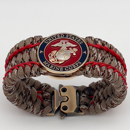 Thick and comfortable braided United States Marine Corps bracelet featuring a 24K gold and silver plated USMC officer Eagle Globe and Anchor medallion, a gold Cobra style tactical buckle and woven with Desert Camo 550 paracord and Imperial Red micro cord.