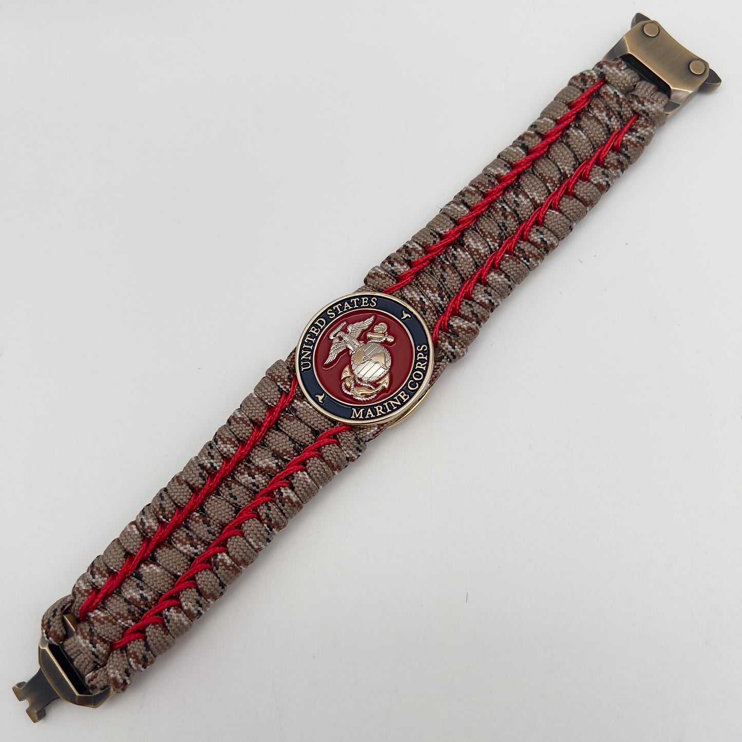 Thick and comfortable braided United States Marine Corps bracelet featuring a 24K gold and silver plated USMC officer Eagle Globe and Anchor medallion, a gold Cobra style tactical buckle and woven with Desert Camo 550 paracord and Imperial Red micro cord.