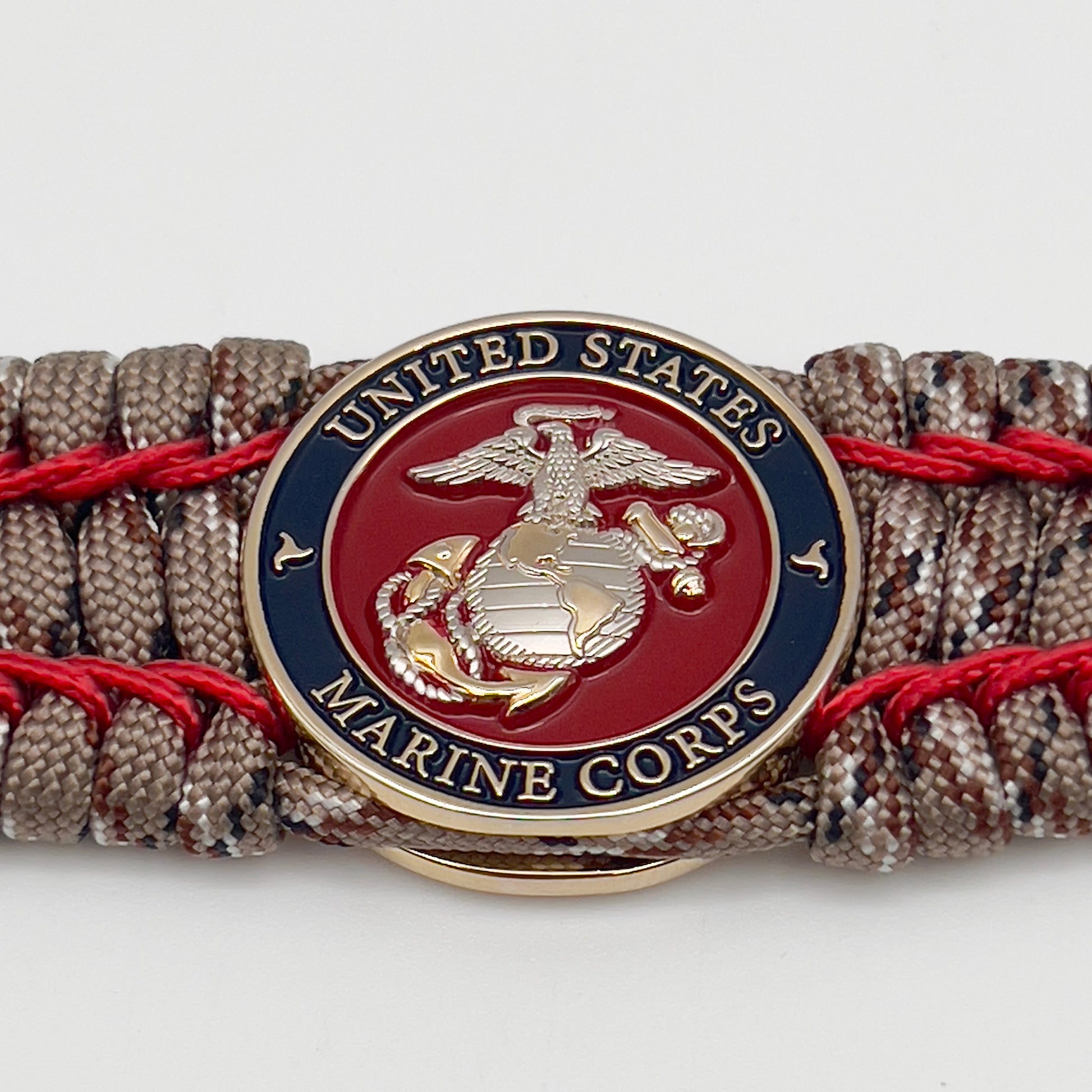 Thick and comfortable braided United States Marine Corps bracelet featuring a 24K gold and silver plated USMC officer Eagle Globe and Anchor medallion, a gold Cobra style tactical buckle and woven with Desert Camo 550 paracord and Imperial Red micro cord.
