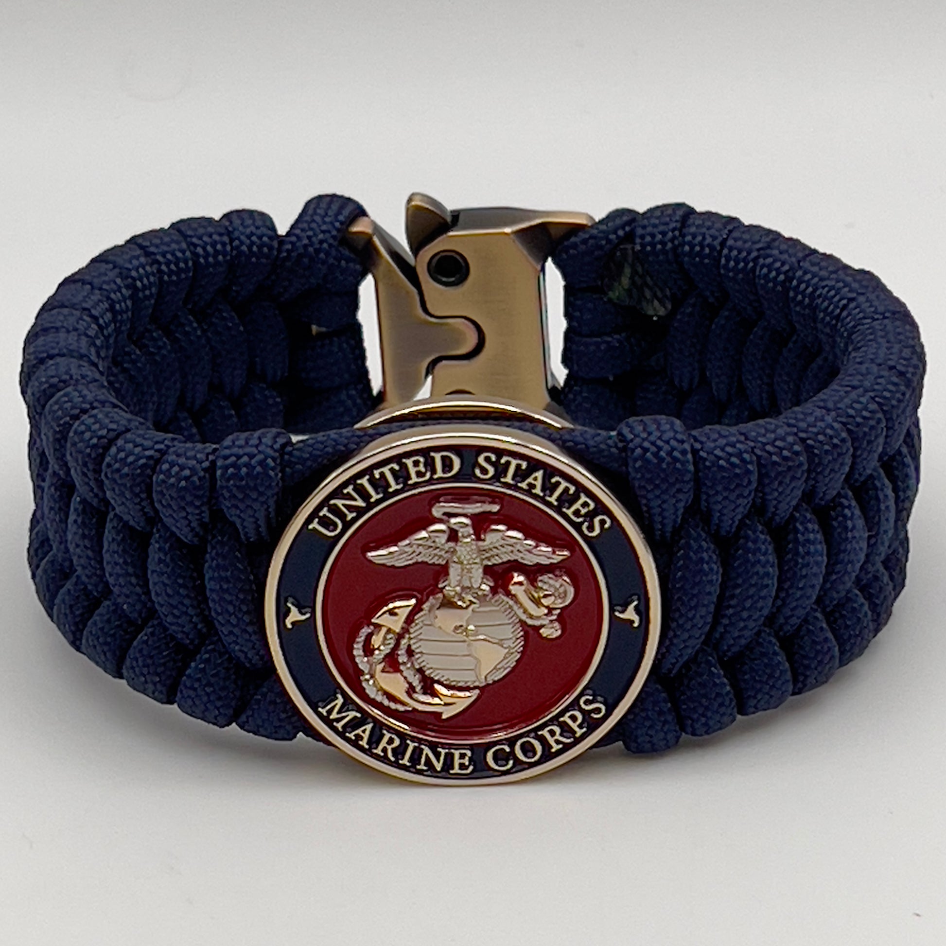 Thick and comfortable braided United States Marine Corps bracelet featuring a 24K gold and silver plated USMC officer Eagle Globe and Anchor medallion, a Cobra style tactical buckle and woven with Navy Blue 550 paracord.