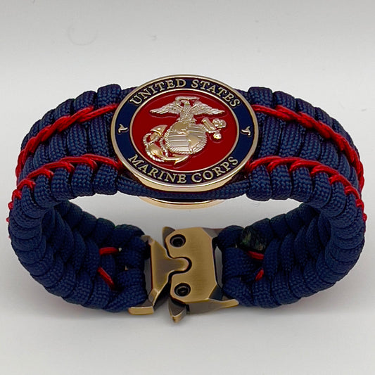 Thick and comfortable braided United States Marine Corps bracelet featuring a 24K gold and silver plated USMC officer Eagle Globe and Anchor medallion, a Cobra style tactical buckle and woven with gold 550 paracord and Imperial Red micro cord.