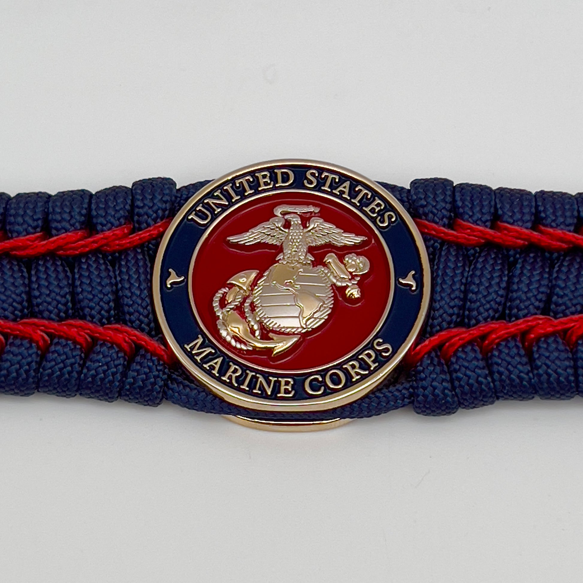 Thick and comfortable braided United States Marine Corps bracelet featuring a 24K gold and silver plated USMC officer Eagle Globe and Anchor medallion, a Cobra style tactical buckle and woven with gold 550 paracord and Imperial Red micro cord.