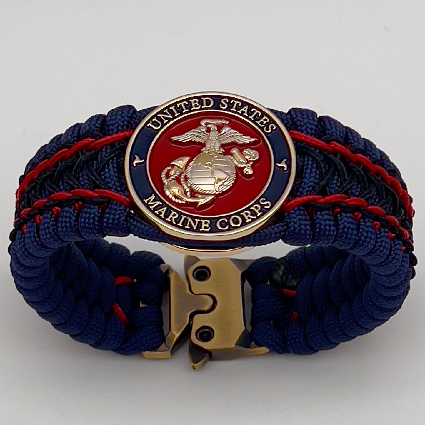 Thick and comfortable braided United States Marine Corps bracelet featuring a 24K gold and silver plated USMC officer Eagle Globe and Anchor medallion, a Cobra style tactical buckle and woven with gold 550 paracord and Imperial Red and Black micro cord.