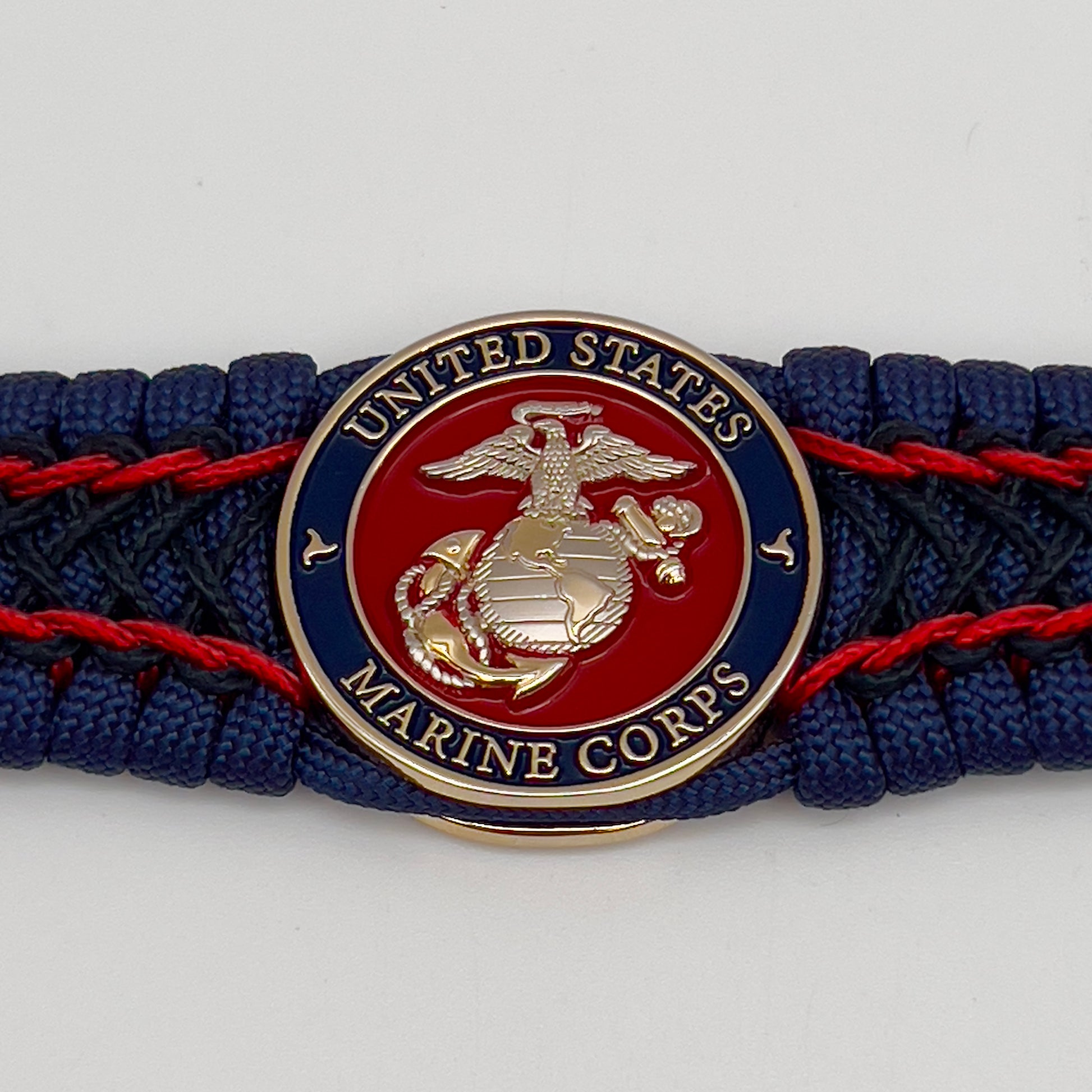 Thick and comfortable braided United States Marine Corps bracelet featuring a 24K gold and silver plated USMC officer Eagle Globe and Anchor medallion, a Cobra style tactical buckle and woven with gold 550 paracord and Imperial Red and Black micro cord.