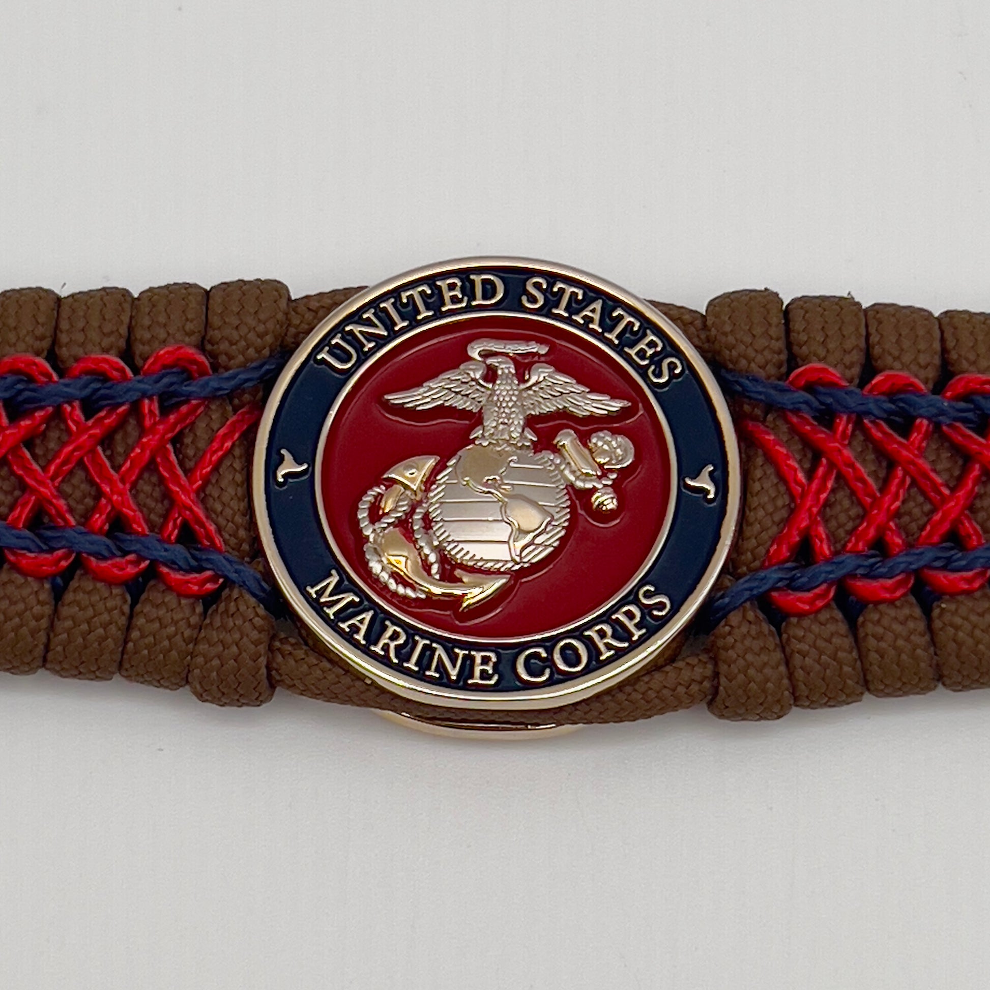 Thick and comfortable braided United States Marine Corps bracelet featuring a 24K gold and silver plated USMC officer Eagle Globe and Anchor medallion, a Cobra style tactical buckle and woven with Coyote Brown 550 paracord and Imperial Red and Navy Blue micro cord.