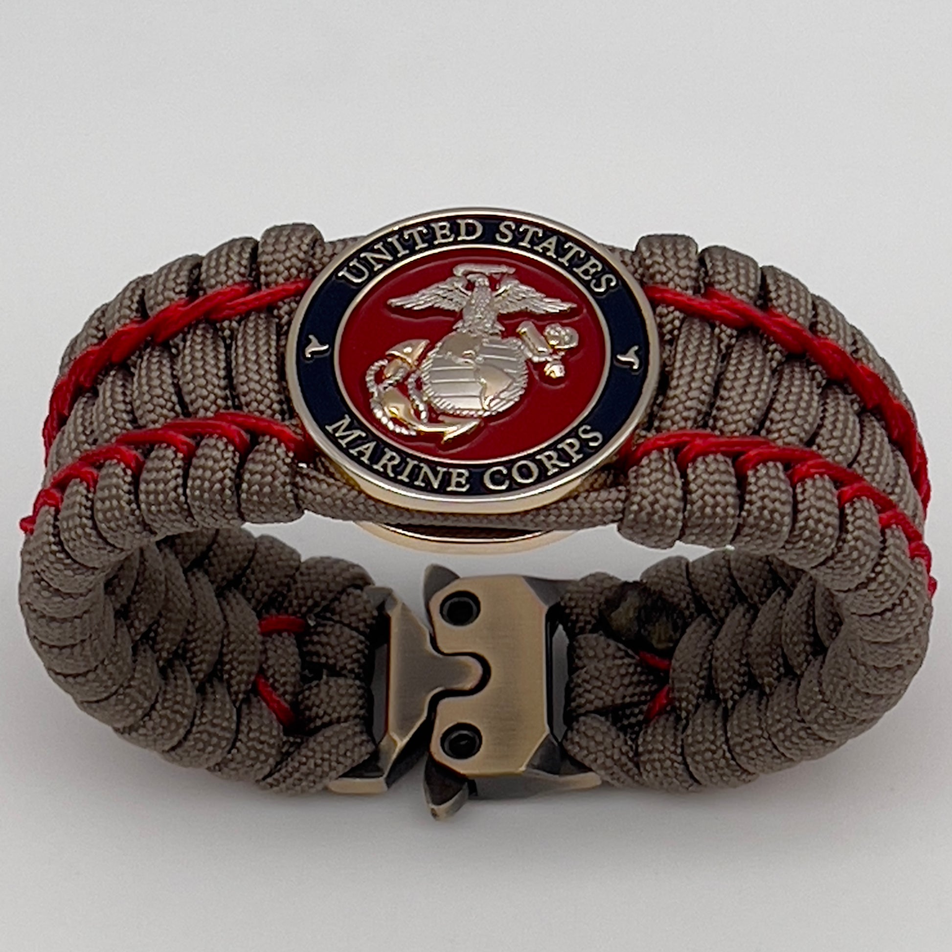 Thick, semi-rigid and comfortable braided United States Marine Corps bracelet featuring a 24K gold and silver plated USMC officer Eagle Globe and Anchor medallion, a gold Cobra style tactical buckle and woven with tan 550 paracord and Imperial Red micro cord.