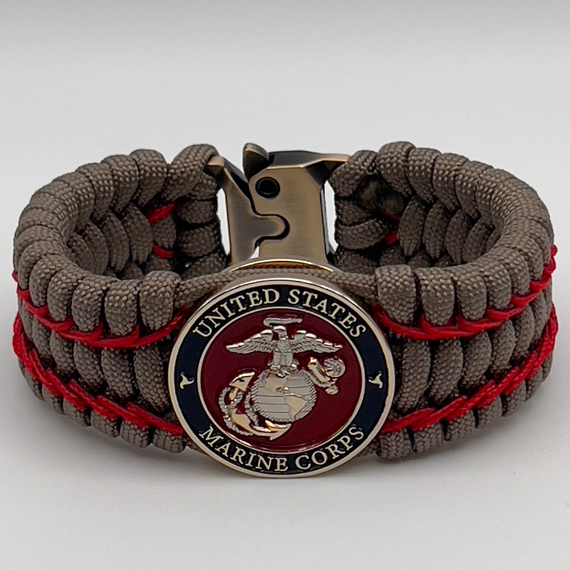 Thick, semi-rigid and comfortable braided United States Marine Corps bracelet featuring a 24K gold and silver plated USMC officer Eagle Globe and Anchor medallion, a gold Cobra style tactical buckle and woven with tan 550 paracord and Imperial Red micro cord.