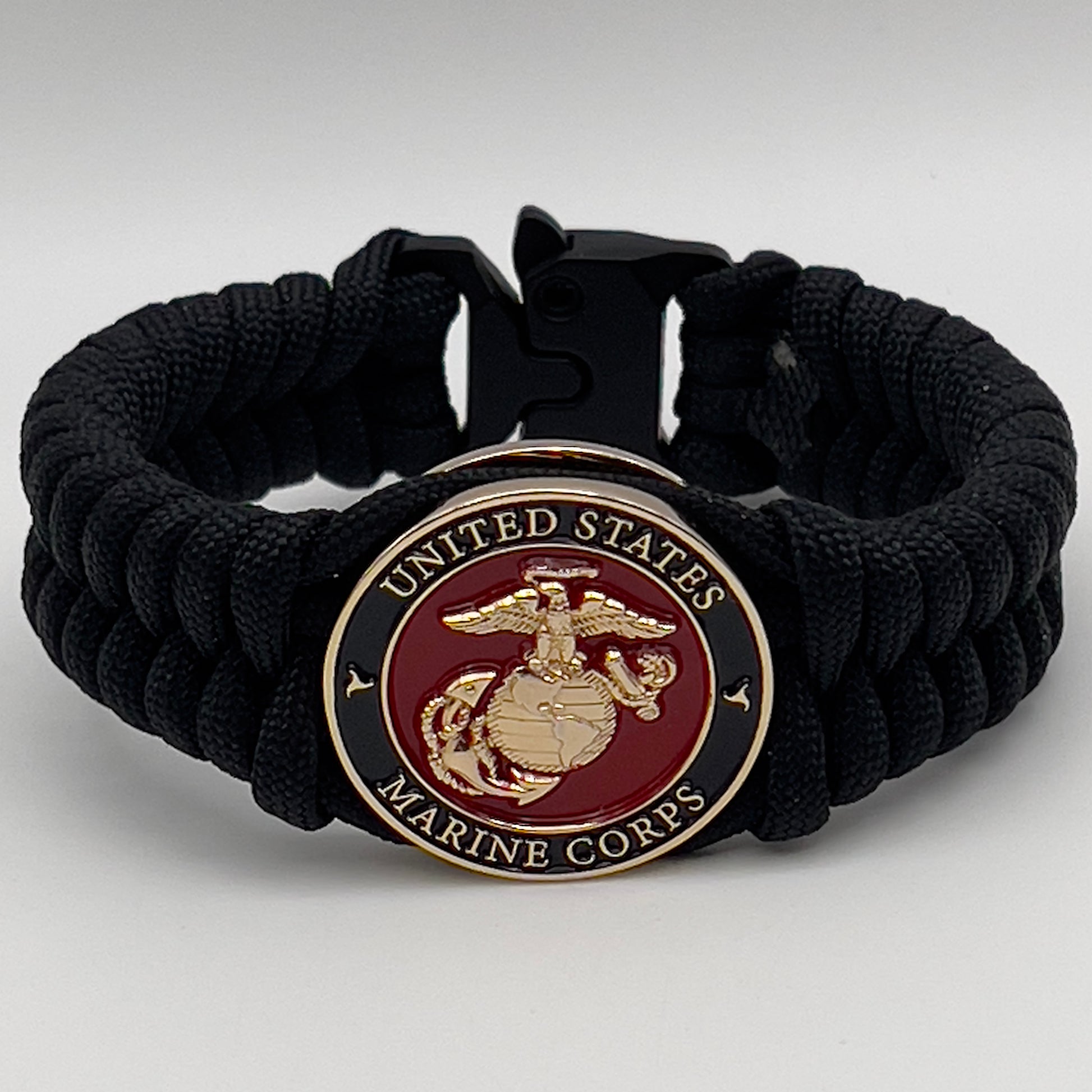 Thick, semi-rigid and comfortable braided United States Marine Corps bracelet featuring a 24K gold plated USMC officer Eagle Globe and Anchor medallion, a black Cobra style tactical buckle and woven with black 550 paracord.