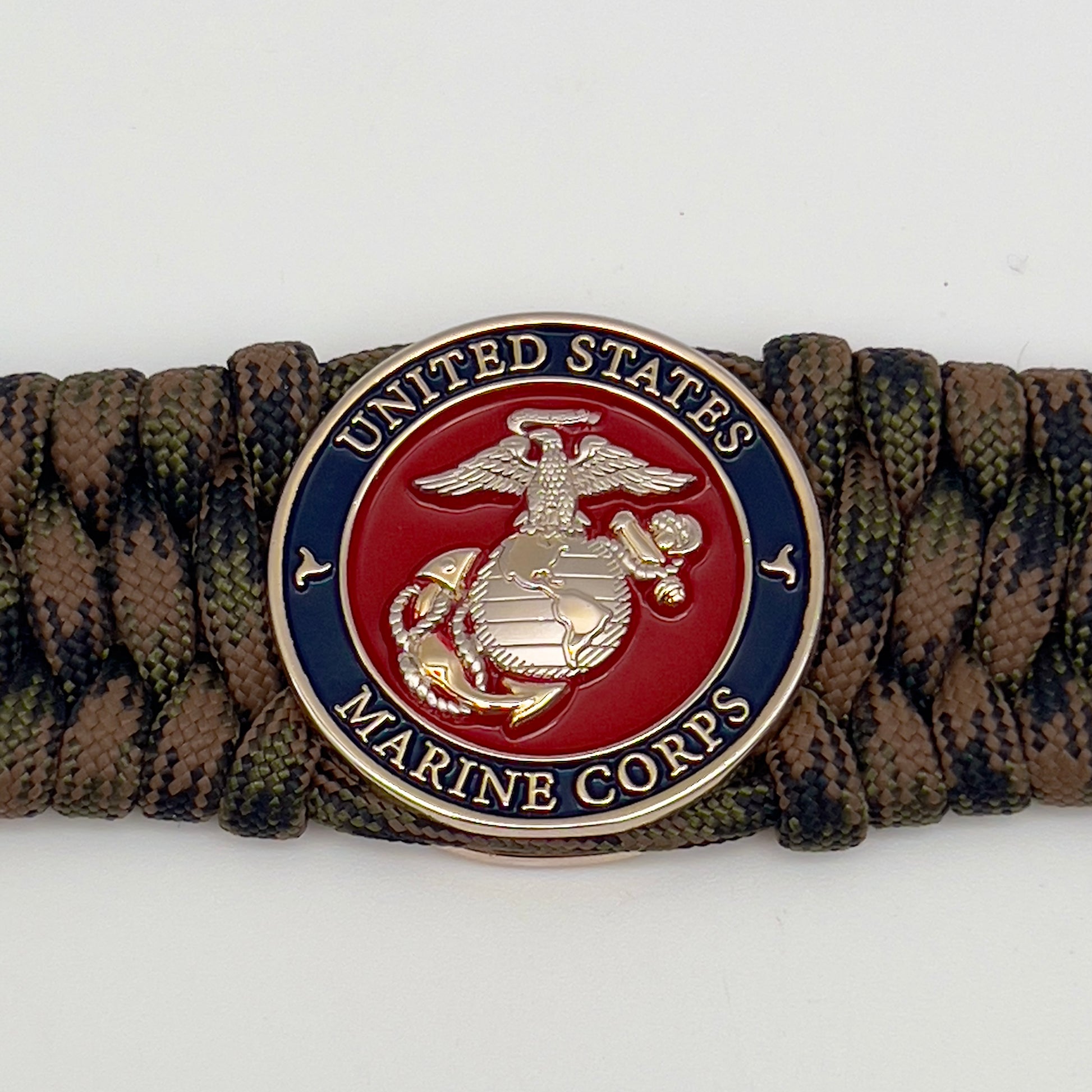 Thick, rigid and comfortable braided United States Marine Corps bracelet featuring a 24K gold and silver plated USMC officer Eagle Globe and Anchor medallion, a gold Cobra style tactical buckle and woven with Woodland Camo 550 paracord.