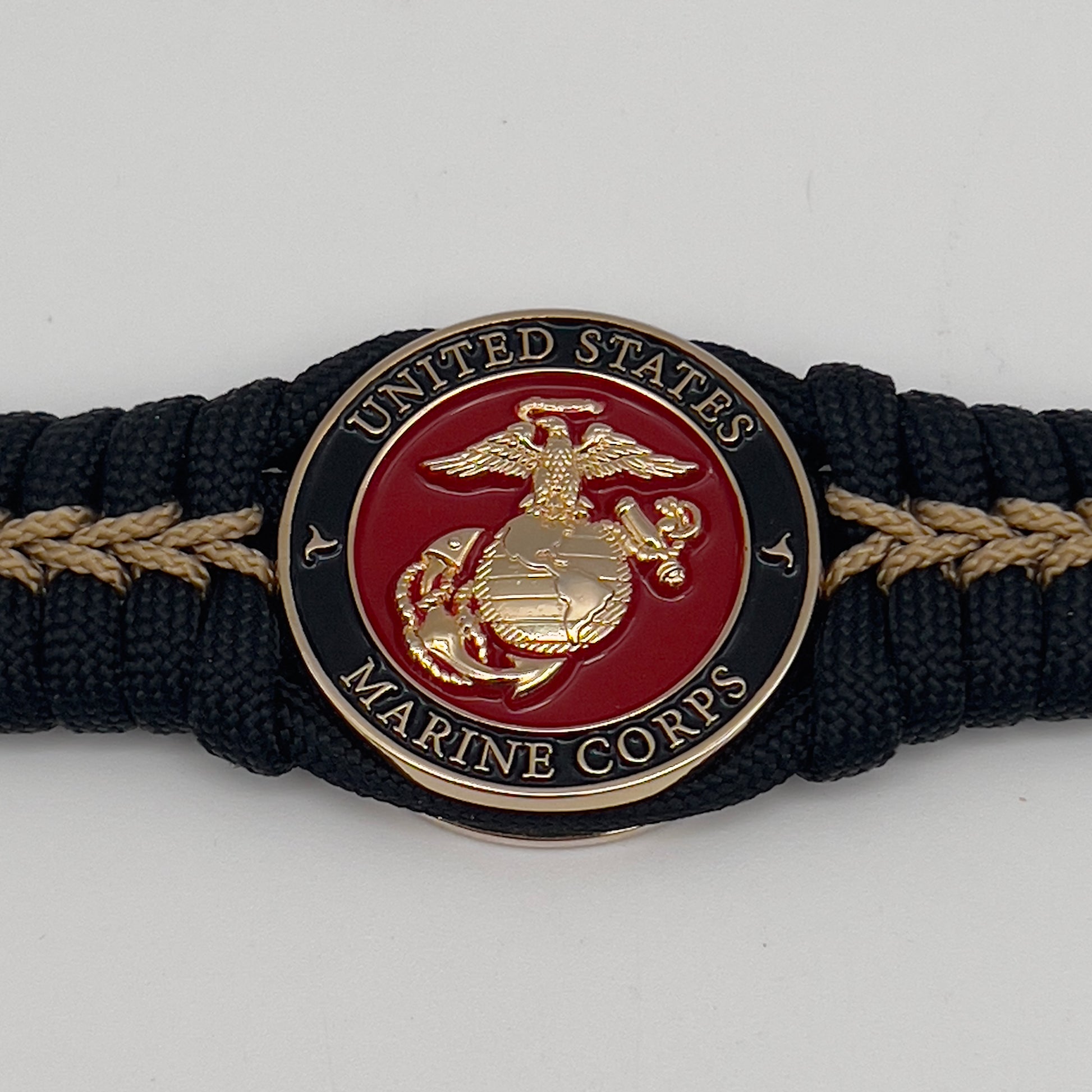Thick, semi-rigid and comfortable braided United States Marine Corps bracelet featuring a 24K gold plated USMC officer Eagle Globe and Anchor medallion, a black Cobra style tactical buckle and woven with black 550 paracord and gold micro cord.