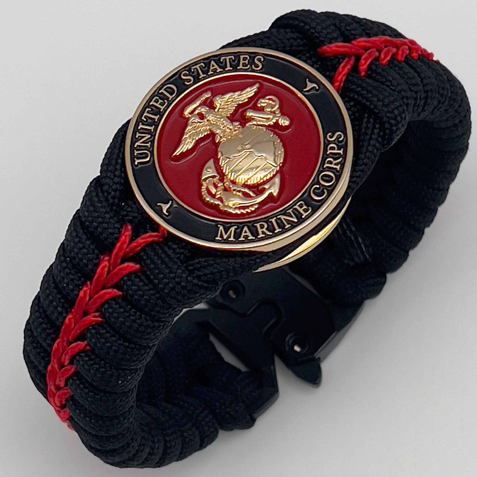 Thick, semi-rigid and comfortable braided United States Marine Corps bracelet featuring a 24K gold plated USMC officer Eagle Globe and Anchor medallion, a black Cobra style tactical buckle and woven with black 550 paracord and Imperial Red micro cord.