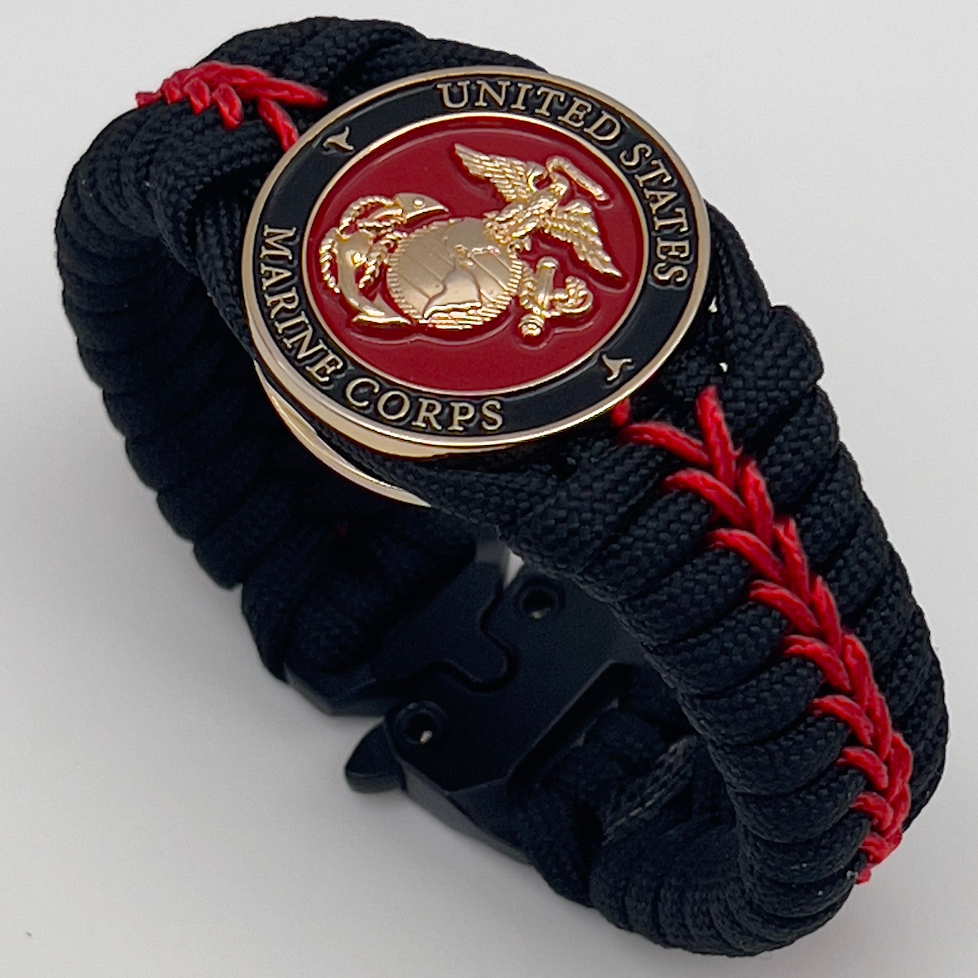 Thick, semi-rigid and comfortable braided United States Marine Corps bracelet featuring a 24K gold plated USMC officer Eagle Globe and Anchor medallion, a black Cobra style tactical buckle and woven with black 550 paracord and Imperial Red micro cord.