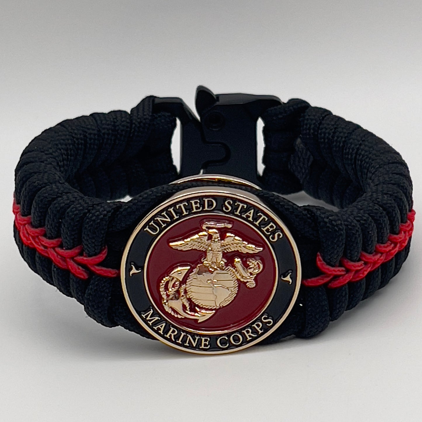Thick, semi-rigid and comfortable braided United States Marine Corps bracelet featuring a 24K gold plated USMC officer Eagle Globe and Anchor medallion, a black Cobra style tactical buckle and woven with black 550 paracord and Imperial Red micro cord.