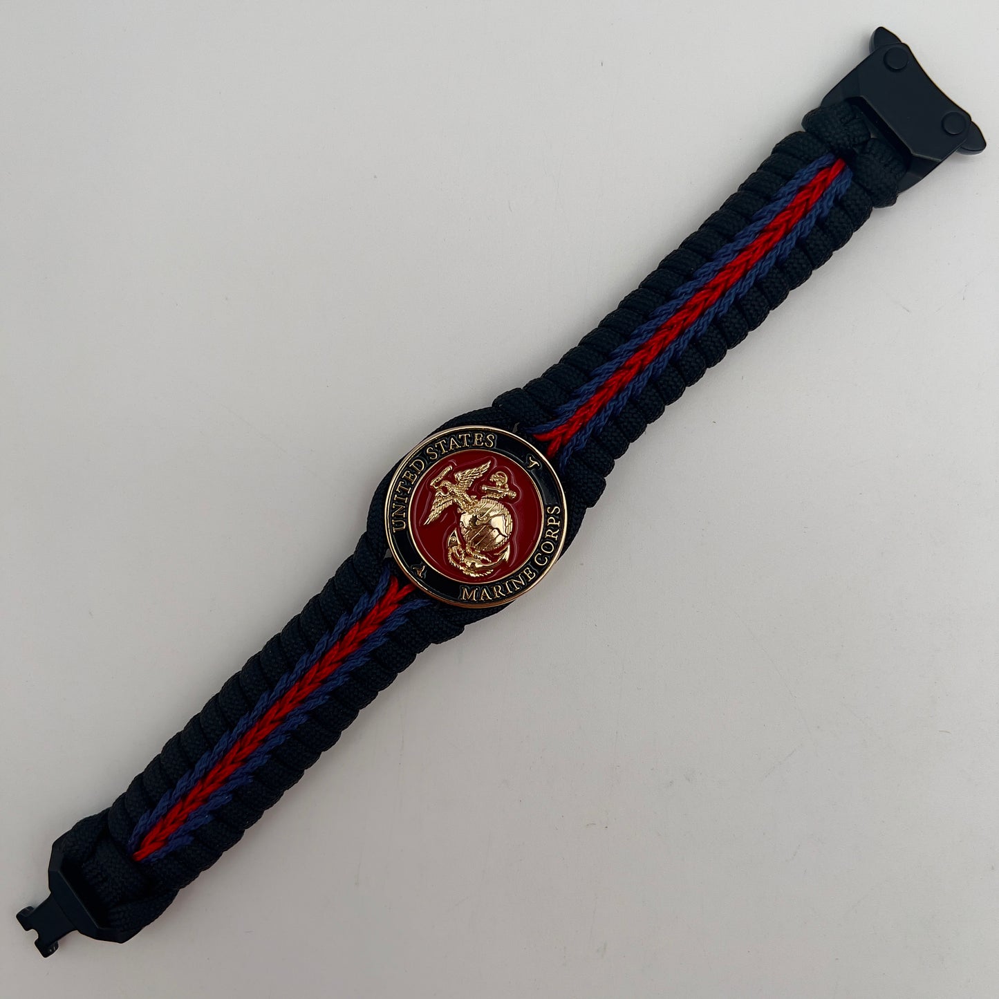 Thick, rigid and comfortable braided United States Marine Corps bracelet featuring a 24K gold plated USMC officer Eagle Globe and Anchor medallion, a black Cobra style tactical buckle and woven with black 550, Imperial red and Navy Blue micro paracord.