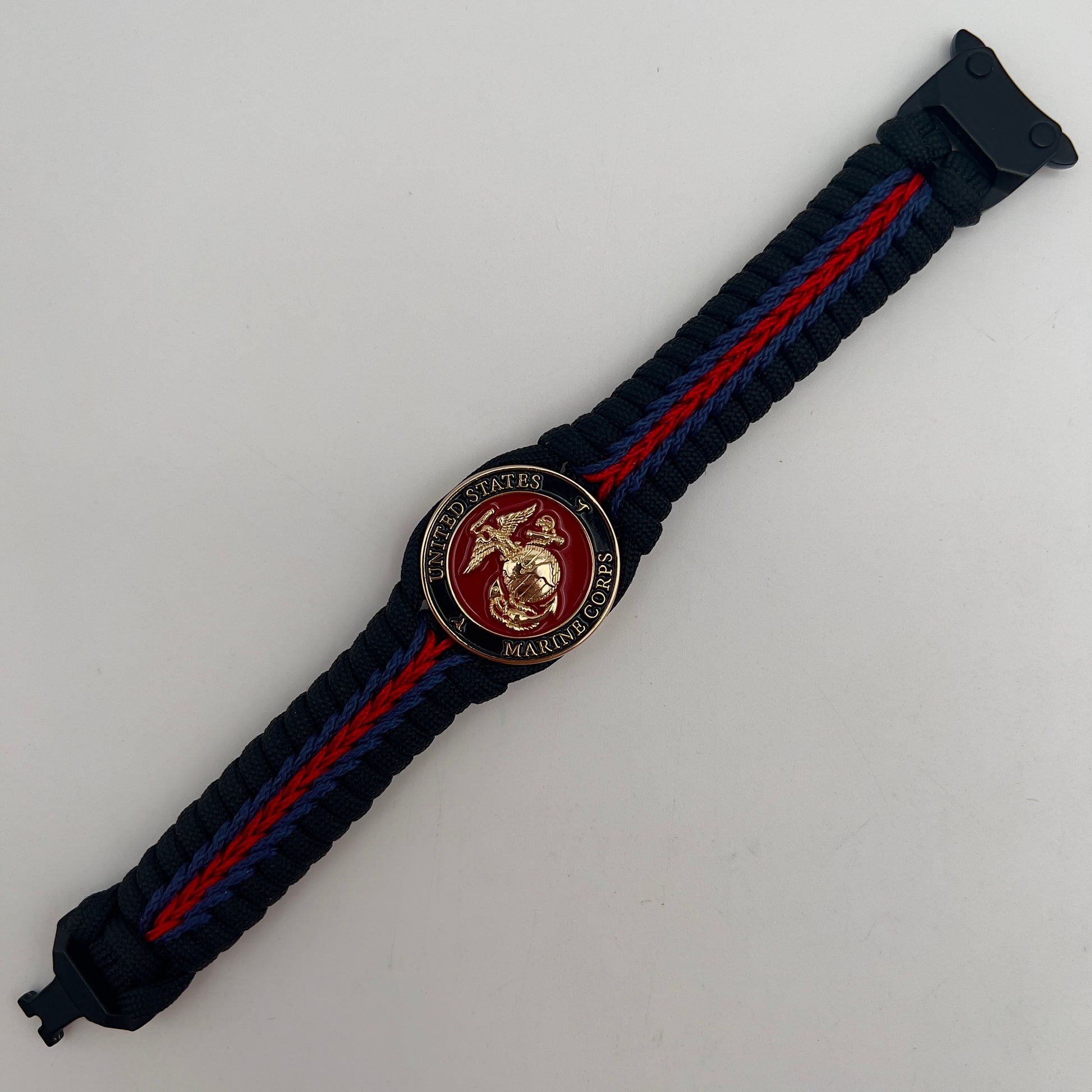 Thick, rigid and comfortable braided United States Marine Corps bracelet featuring a 24K gold plated USMC officer Eagle Globe and Anchor medallion, a black Cobra style tactical buckle and woven with black 550, Imperial red and Navy Blue micro paracord.