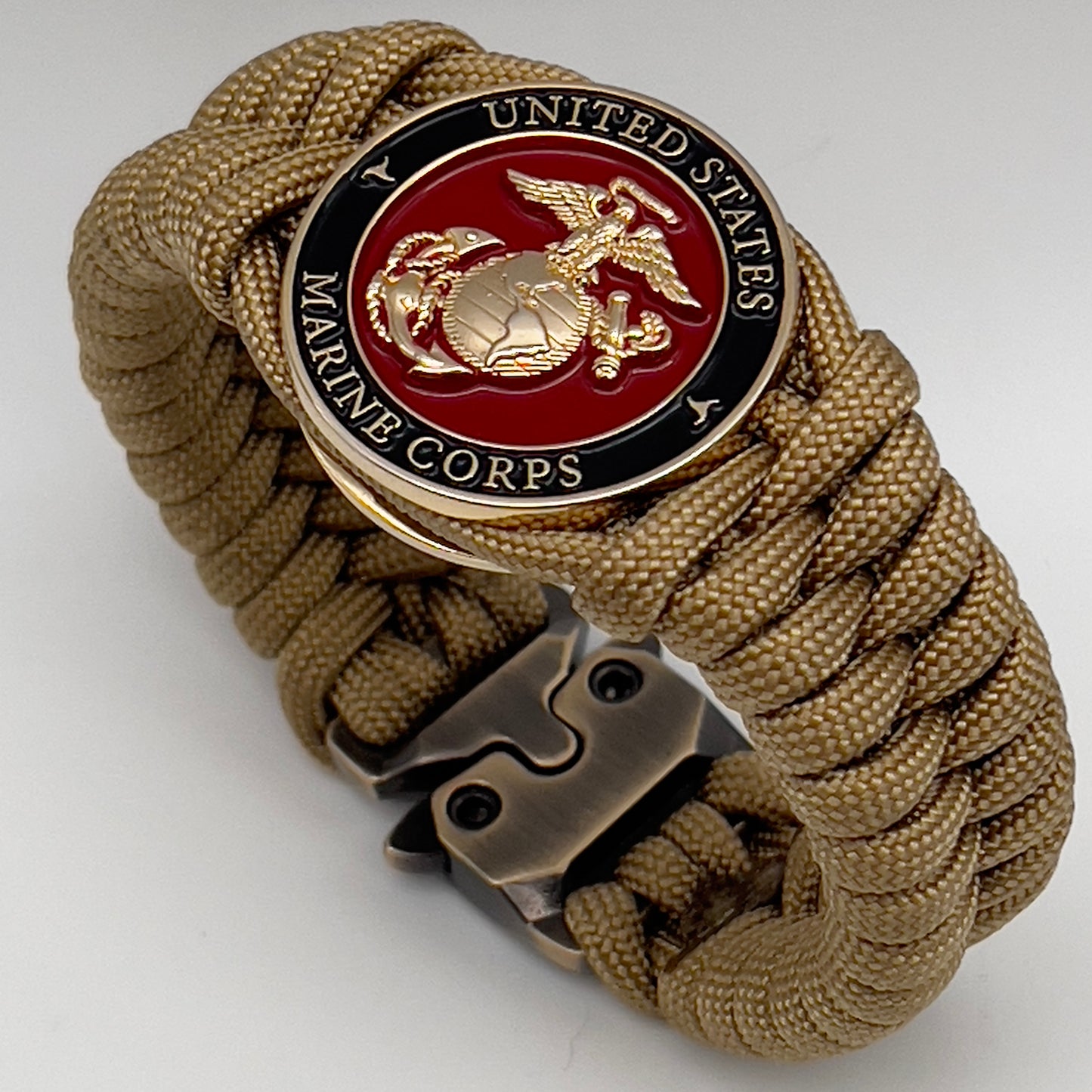 Thick, semi-rigid and comfortable braided United States Marine Corps bracelet featuring a 24K gold plated USMC officer Eagle Globe and Anchor medallion, a gold Cobra style tactical buckle and woven with gold 550 paracord.