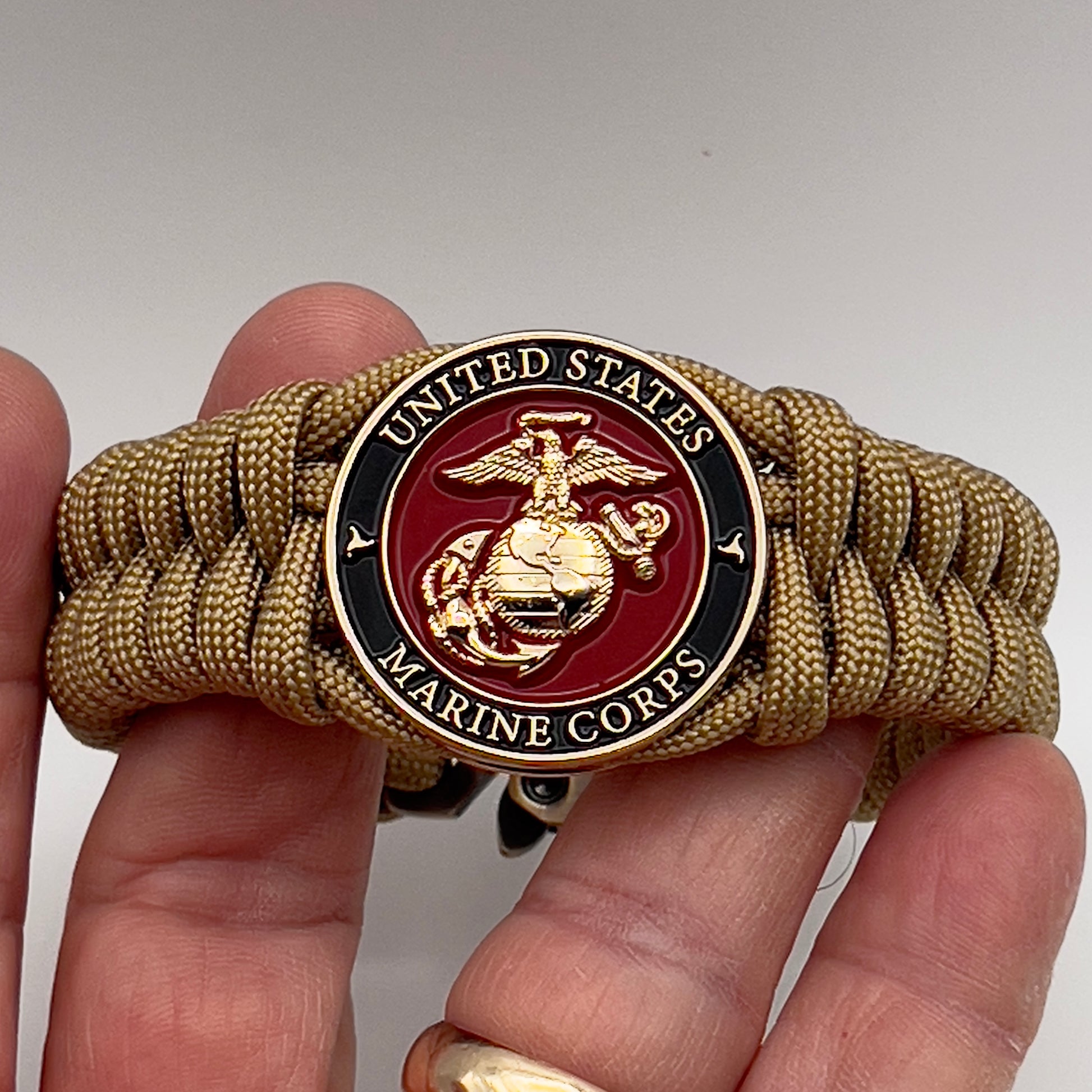 Thick, semi-rigid and comfortable braided United States Marine Corps bracelet featuring a 24K gold plated USMC officer Eagle Globe and Anchor medallion, a gold Cobra style tactical buckle and woven with gold 550 paracord.