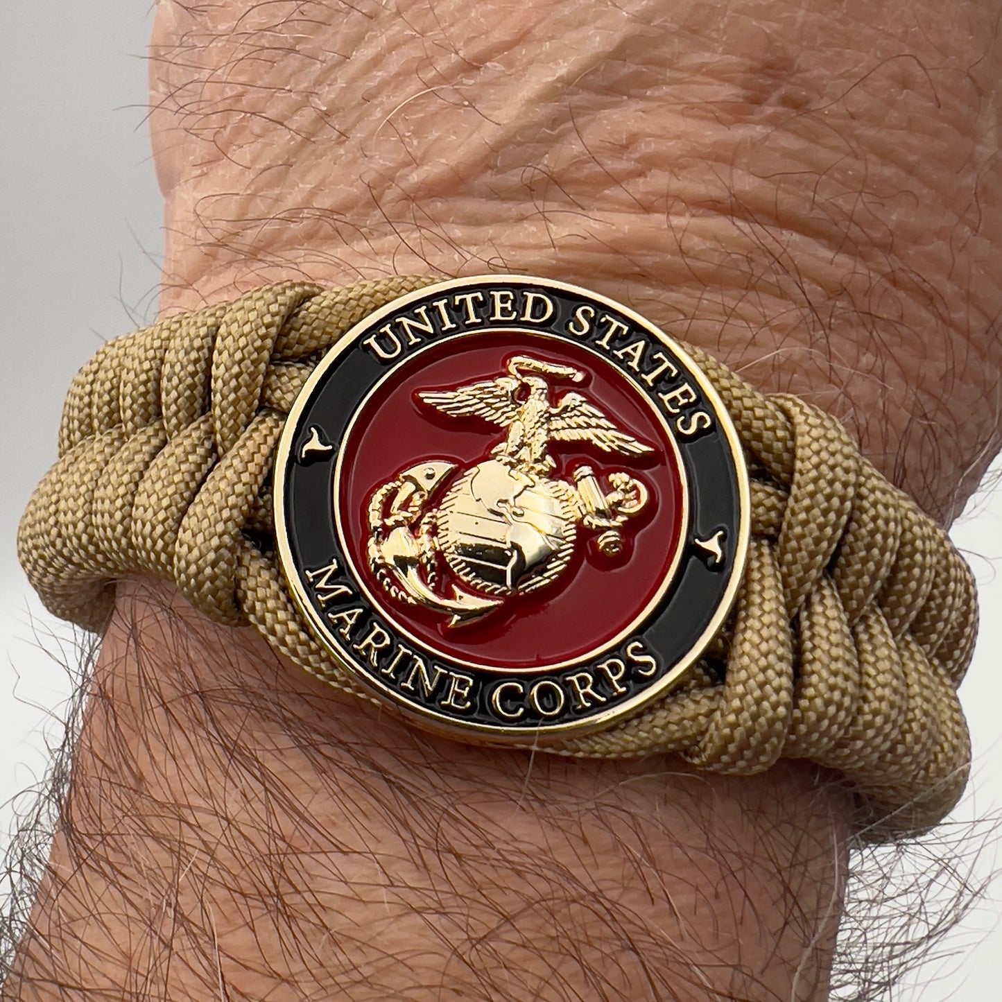 Thick, semi-rigid and comfortable braided United States Marine Corps bracelet featuring a 24K gold plated USMC officer Eagle Globe and Anchor medallion, a gold Cobra style tactical buckle and woven with gold 550 paracord.