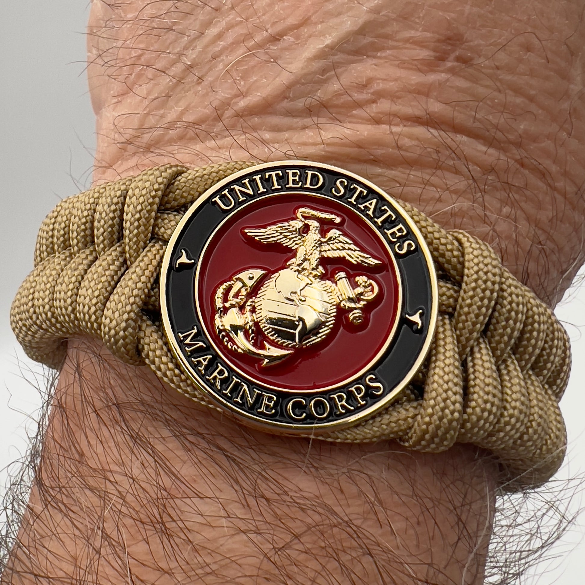 Thick, semi-rigid and comfortable braided United States Marine Corps bracelet featuring a 24K gold plated USMC officer Eagle Globe and Anchor medallion, a gold Cobra style tactical buckle and woven with gold 550 paracord.