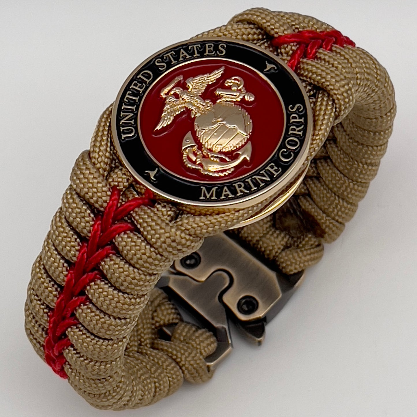 Thick, semi-rigid and comfortable braided United States Marine Corps bracelet featuring a 24K gold plated USMC officer Eagle Globe and Anchor medallion, a gold Cobra style tactical buckle and woven with gold 550 paracord and Imperial Red micro cord.