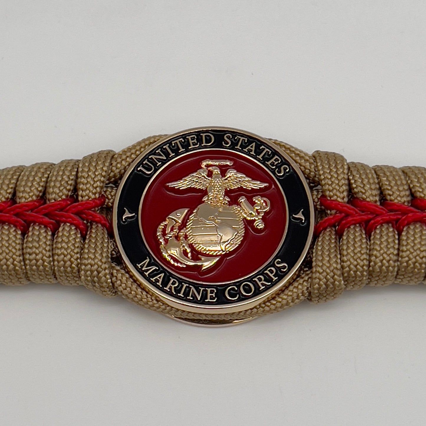 Thick, semi-rigid and comfortable braided United States Marine Corps bracelet featuring a 24K gold plated USMC officer Eagle Globe and Anchor medallion, a gold Cobra style tactical buckle and woven with gold 550 paracord and Imperial Red micro cord.