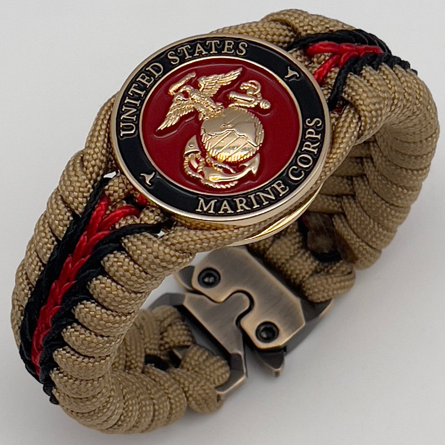 Thick, rigid and comfortable braided United States Marine Corps bracelet featuring a 24K gold plated USMC officer Eagle Globe and Anchor medallion, a gold Cobra style tactical buckle and woven with gold 550 paracord and Imperial Red and black micro cord.
