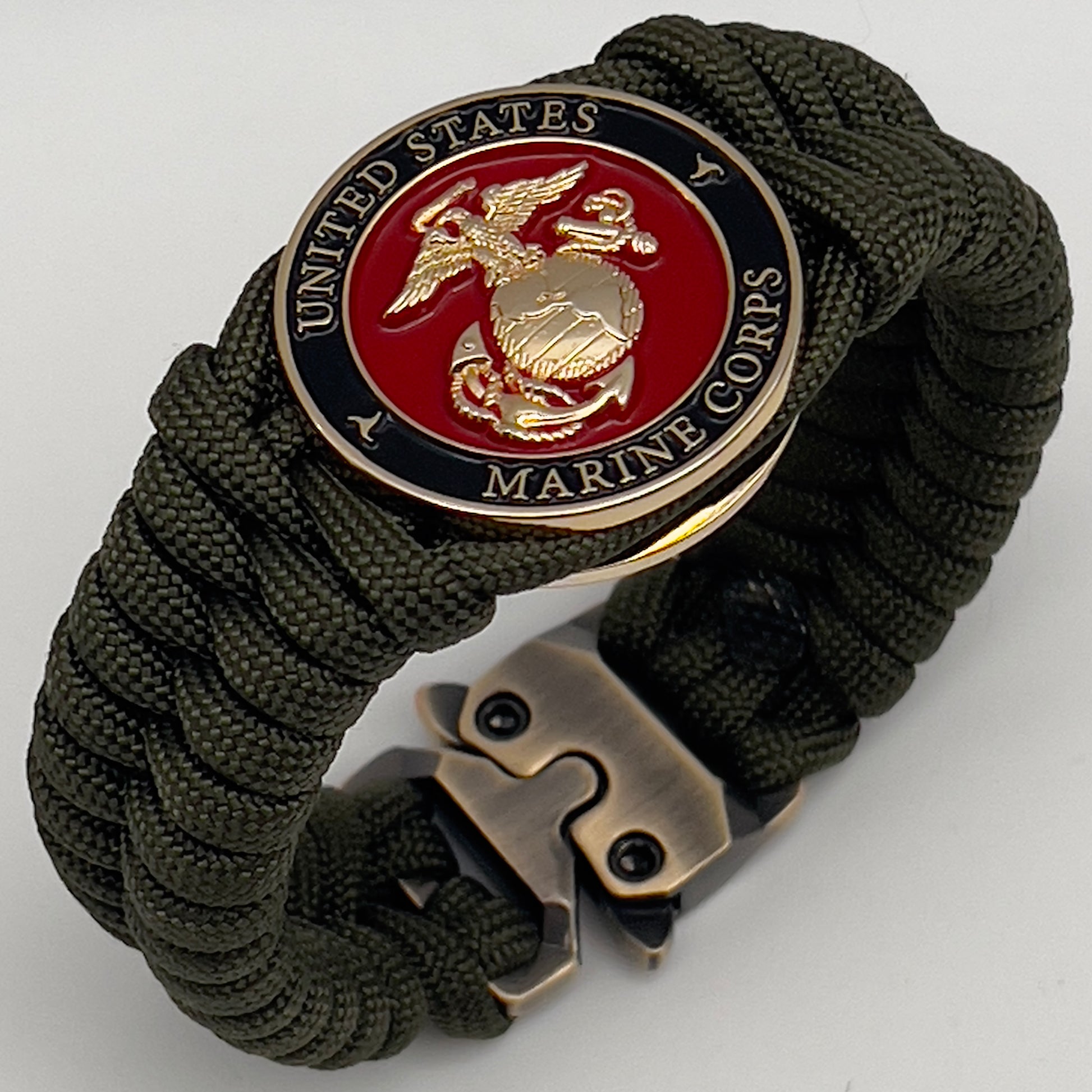 Thick, semi-rigid and comfortable braided United States Marine Corps bracelet featuring a 24K gold plated USMC officer Eagle Globe and Anchor medallion, a gold Cobra style tactical buckle and woven with olive drab 550 paracord.