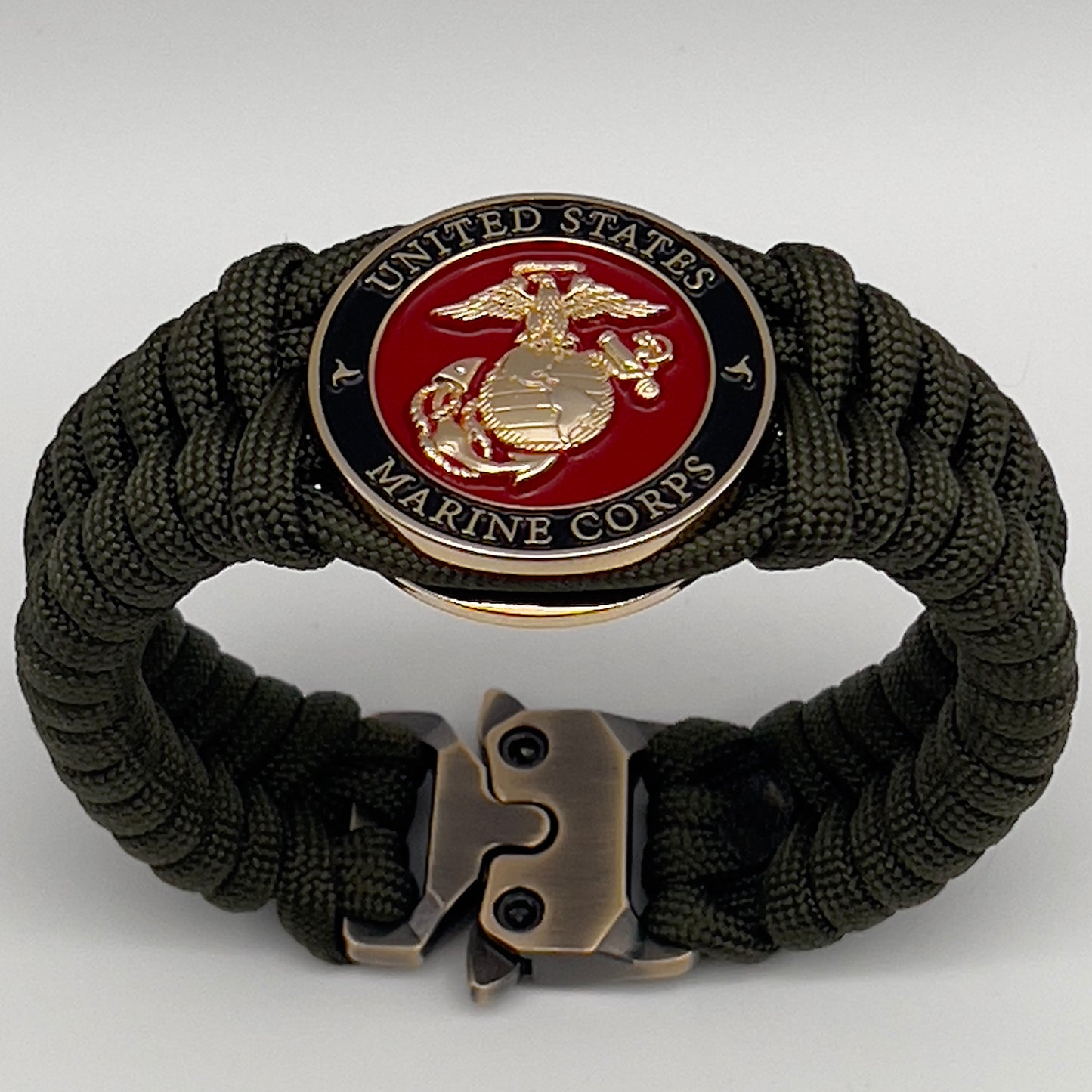 Thick, semi-rigid and comfortable braided United States Marine Corps bracelet featuring a 24K gold plated USMC officer Eagle Globe and Anchor medallion, a gold Cobra style tactical buckle and woven with olive drab 550 paracord.