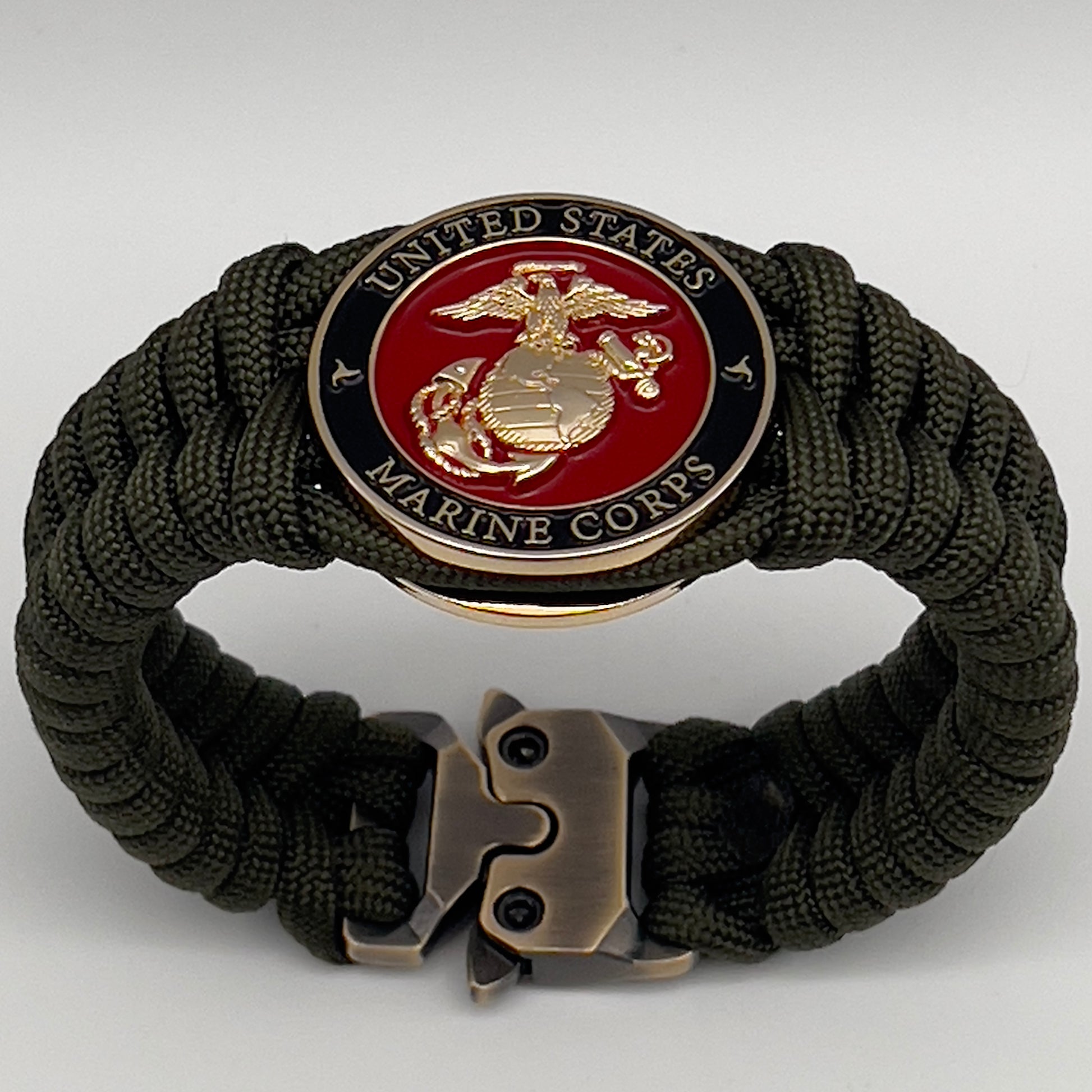 Thick, semi-rigid and comfortable braided United States Marine Corps bracelet featuring a 24K gold plated USMC officer Eagle Globe and Anchor medallion, a gold Cobra style tactical buckle and woven with olive drab 550 paracord.
