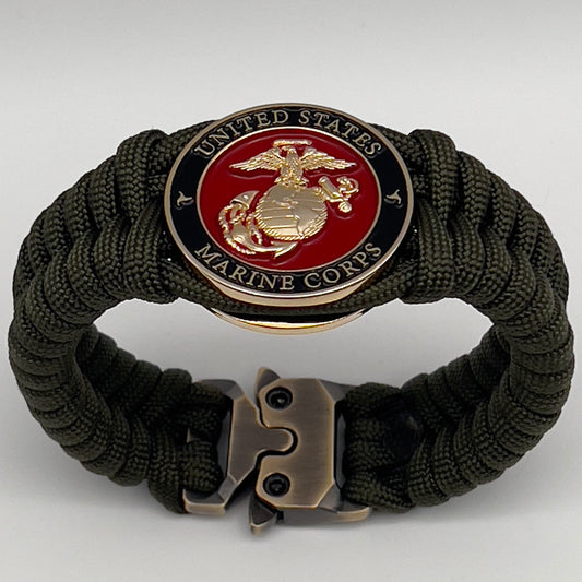 Thick, semi-rigid and comfortable braided United States Marine Corps bracelet featuring a 24K gold plated USMC officer Eagle Globe and Anchor medallion, a gold Cobra style tactical buckle and woven with olive drab 550 paracord.