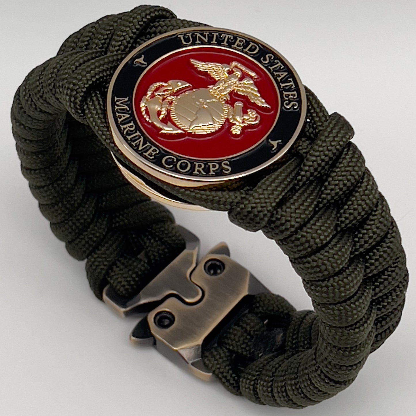 Thick, semi-rigid and comfortable braided United States Marine Corps bracelet featuring a 24K gold plated USMC officer Eagle Globe and Anchor medallion, a gold Cobra style tactical buckle and woven with olive drab 550 paracord.