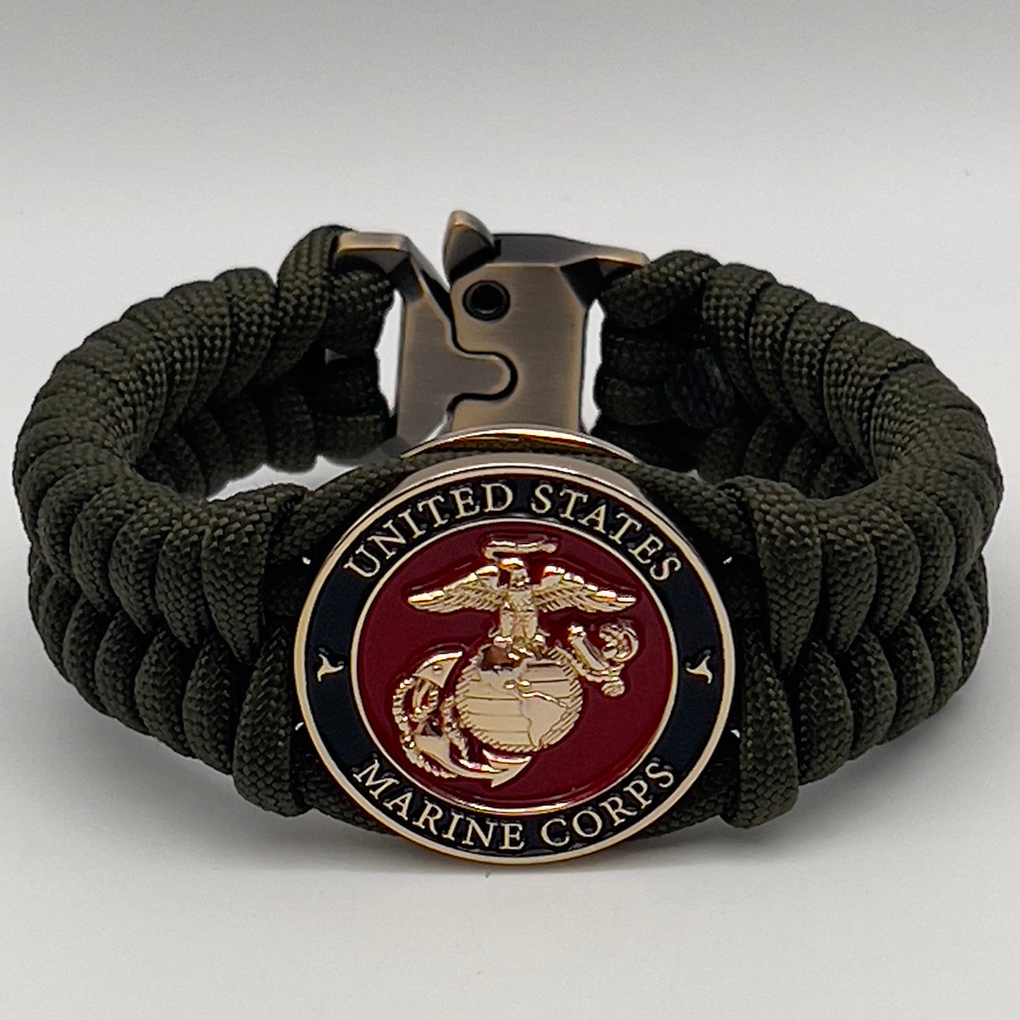 Thick, semi-rigid and comfortable braided United States Marine Corps bracelet featuring a 24K gold plated USMC officer Eagle Globe and Anchor medallion, a gold Cobra style tactical buckle and woven with olive drab 550 paracord.