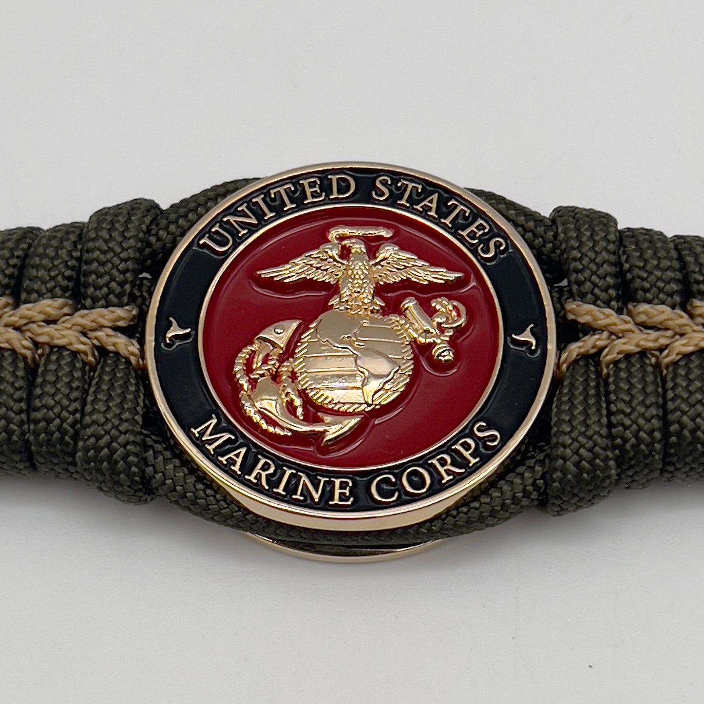 Thick, semi-rigid and comfortable braided United States Marine Corps bracelet featuring a 24K gold plated USMC officer Eagle Globe and Anchor medallion, a gold Cobra style tactical buckle and woven with olive drab 550 paracord and gold micro cord.