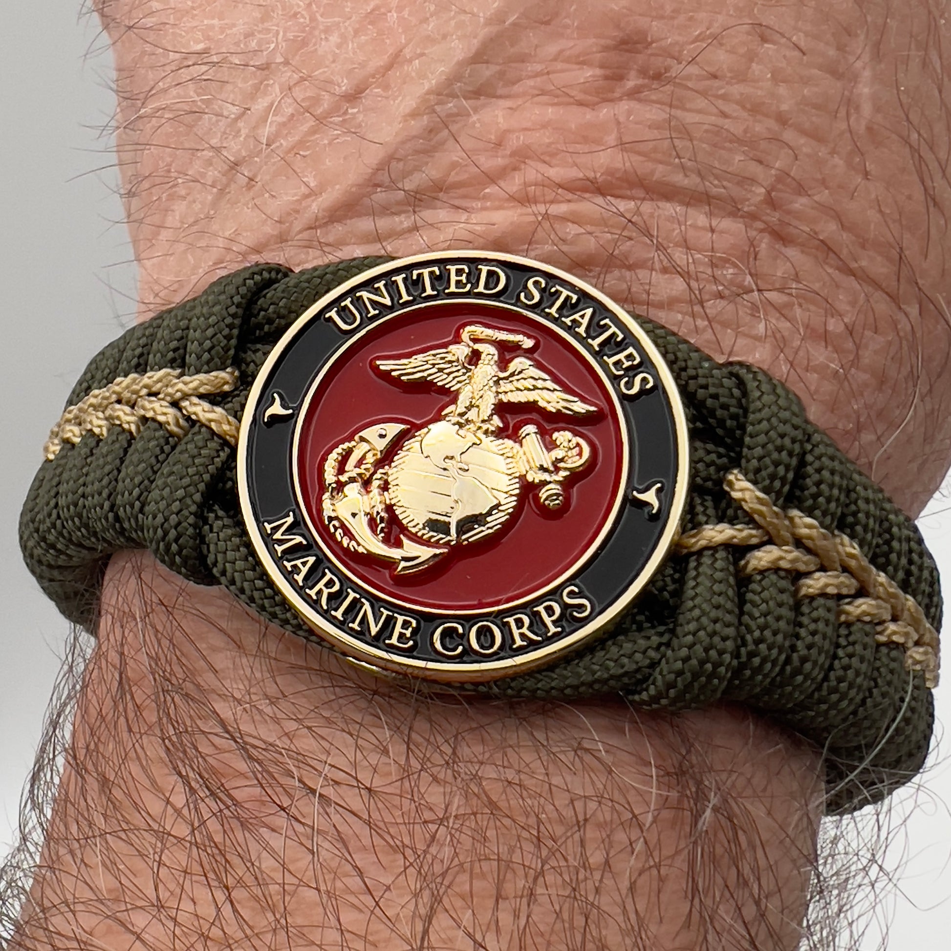 Thick, semi-rigid and comfortable braided United States Marine Corps bracelet featuring a 24K gold plated USMC officer Eagle Globe and Anchor medallion, a gold Cobra style tactical buckle and woven with olive drab 550 paracord and gold micro cord.