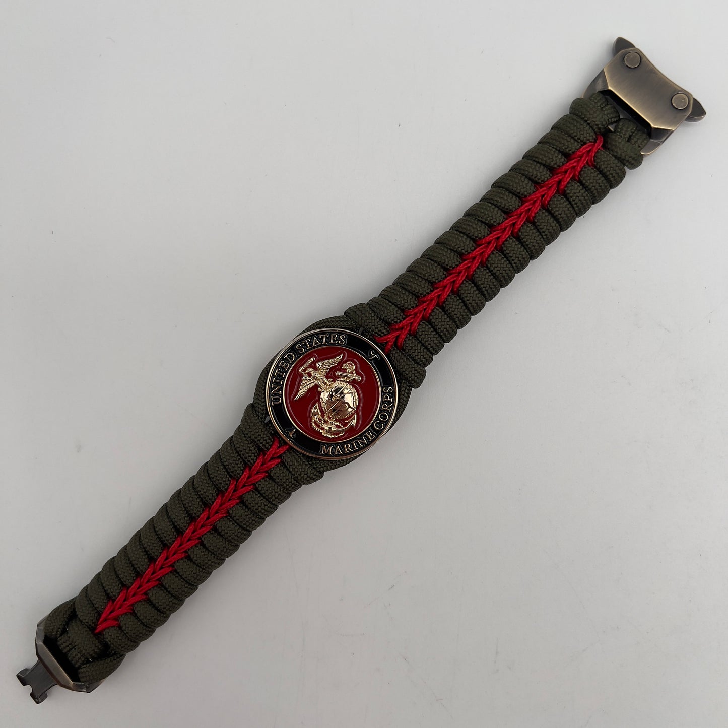 Thick, semi-rigid and comfortable braided United States Marine Corps bracelet featuring a 24K gold plated USMC officer Eagle Globe and Anchor medallion, a gold Cobra style tactical buckle and woven with olive drab 550 paracord and Imperial Red micro cord.