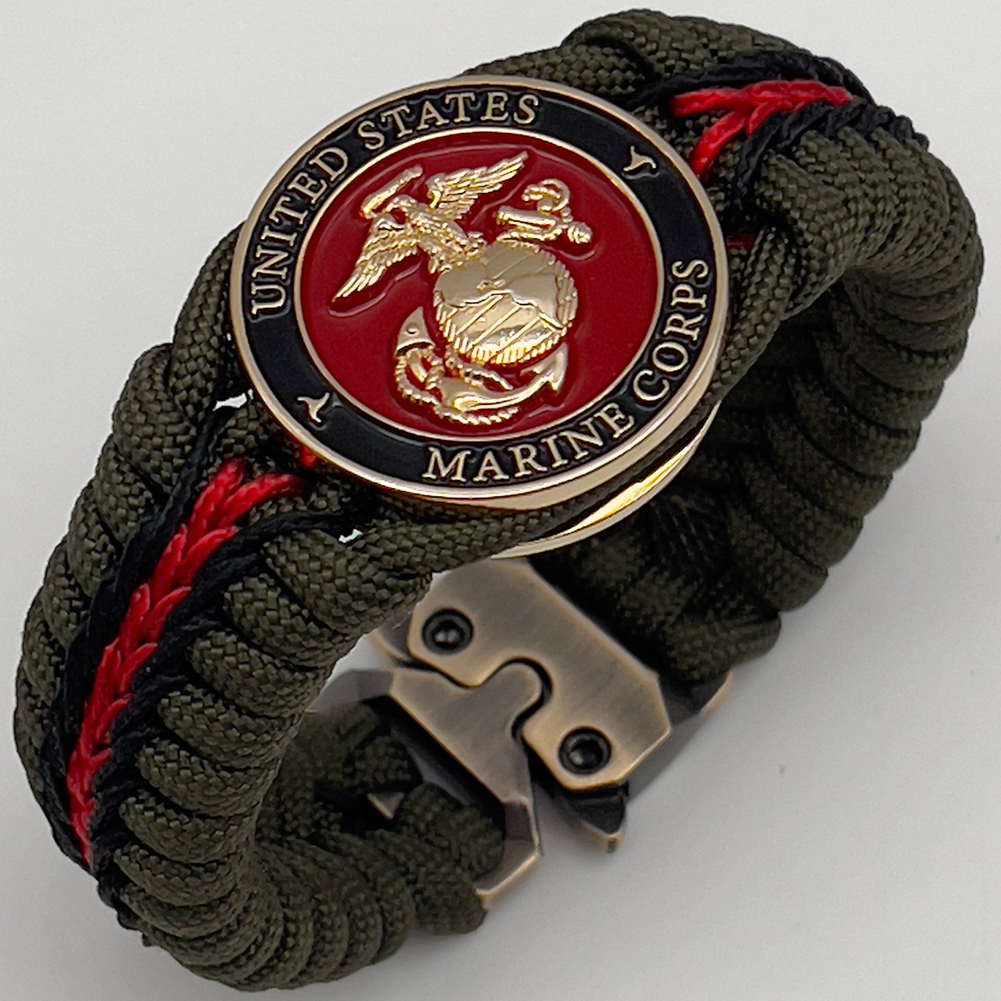 Thick, rigid and comfortable braided United States Marine Corps bracelet featuring a 24K gold plated USMC officer Eagle Globe and Anchor medallion, a gold Cobra style tactical buckle and woven with olive drab 550 paracord and black and Imperial red micro cord.