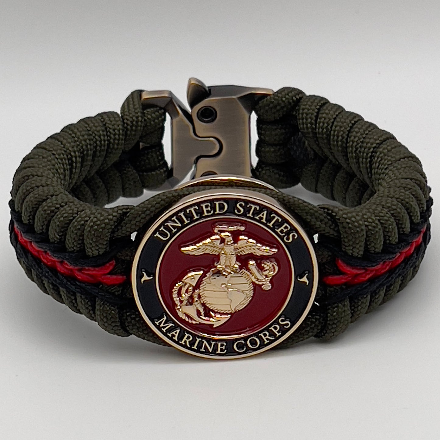 Thick, rigid and comfortable braided United States Marine Corps bracelet featuring a 24K gold plated USMC officer Eagle Globe and Anchor medallion, a gold Cobra style tactical buckle and woven with olive drab 550 paracord and black and Imperial red micro cord.