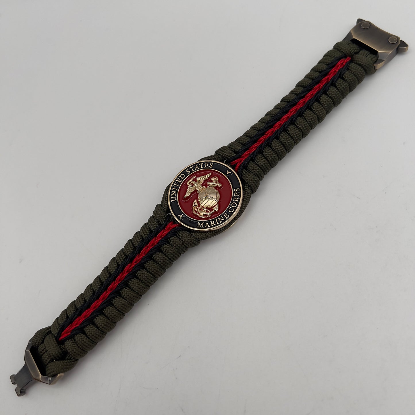 Thick, rigid and comfortable braided United States Marine Corps bracelet featuring a 24K gold plated USMC officer Eagle Globe and Anchor medallion, a gold Cobra style tactical buckle and woven with olive drab 550 paracord and black and Imperial red micro cord.