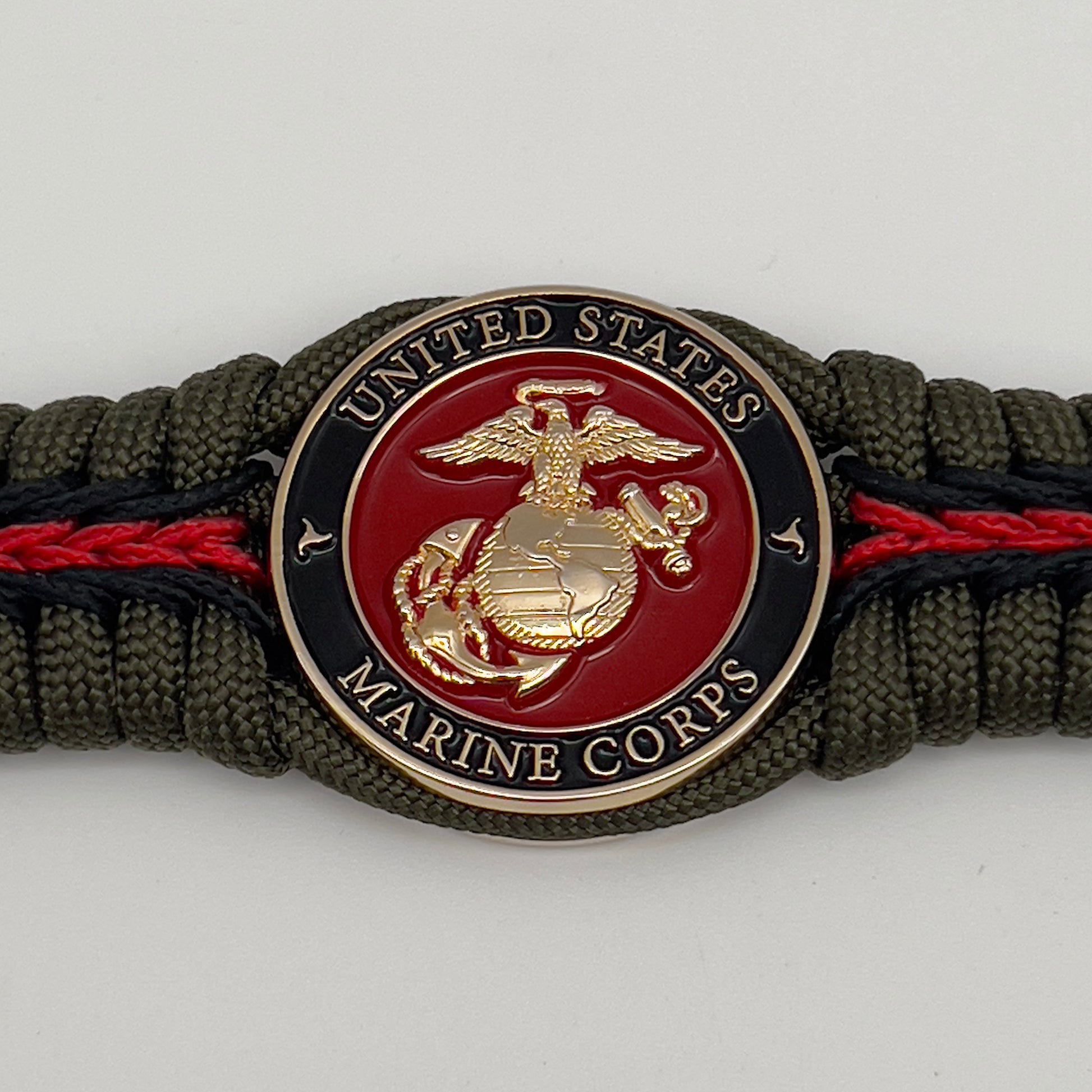 Thick, rigid and comfortable braided United States Marine Corps bracelet featuring a 24K gold plated USMC officer Eagle Globe and Anchor medallion, a gold Cobra style tactical buckle and woven with olive drab 550 paracord and black and Imperial red micro cord.